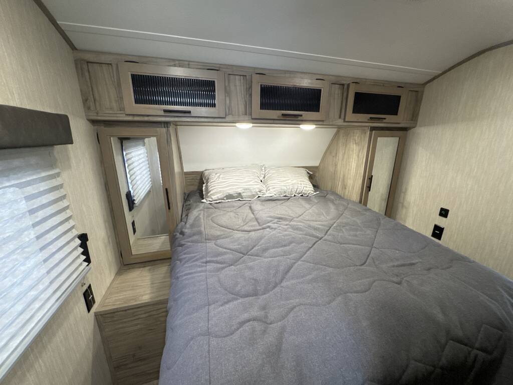Well-appointed RV rental bedroom showing a queen bed, wood-look cabinets, and mirrored closet. Ready for your adventure.. Forest River Cherokee Alpha Wolf 2020