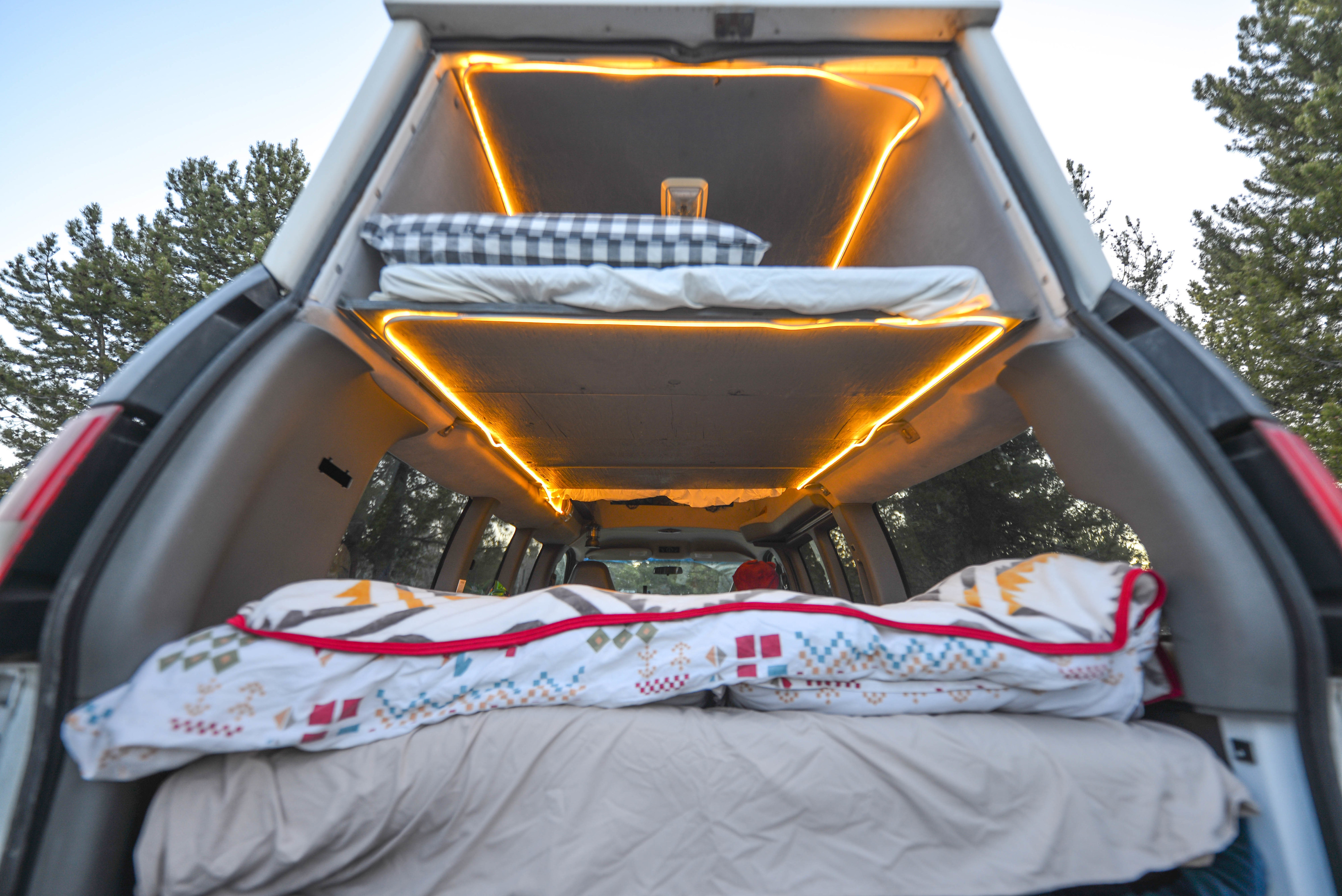 Inside a custom **rv rental**: cozy bunk beds illuminated by warm LED lights, providing a compact sleeping setup for camping trips.. Chevrolet 3500 LS 2006