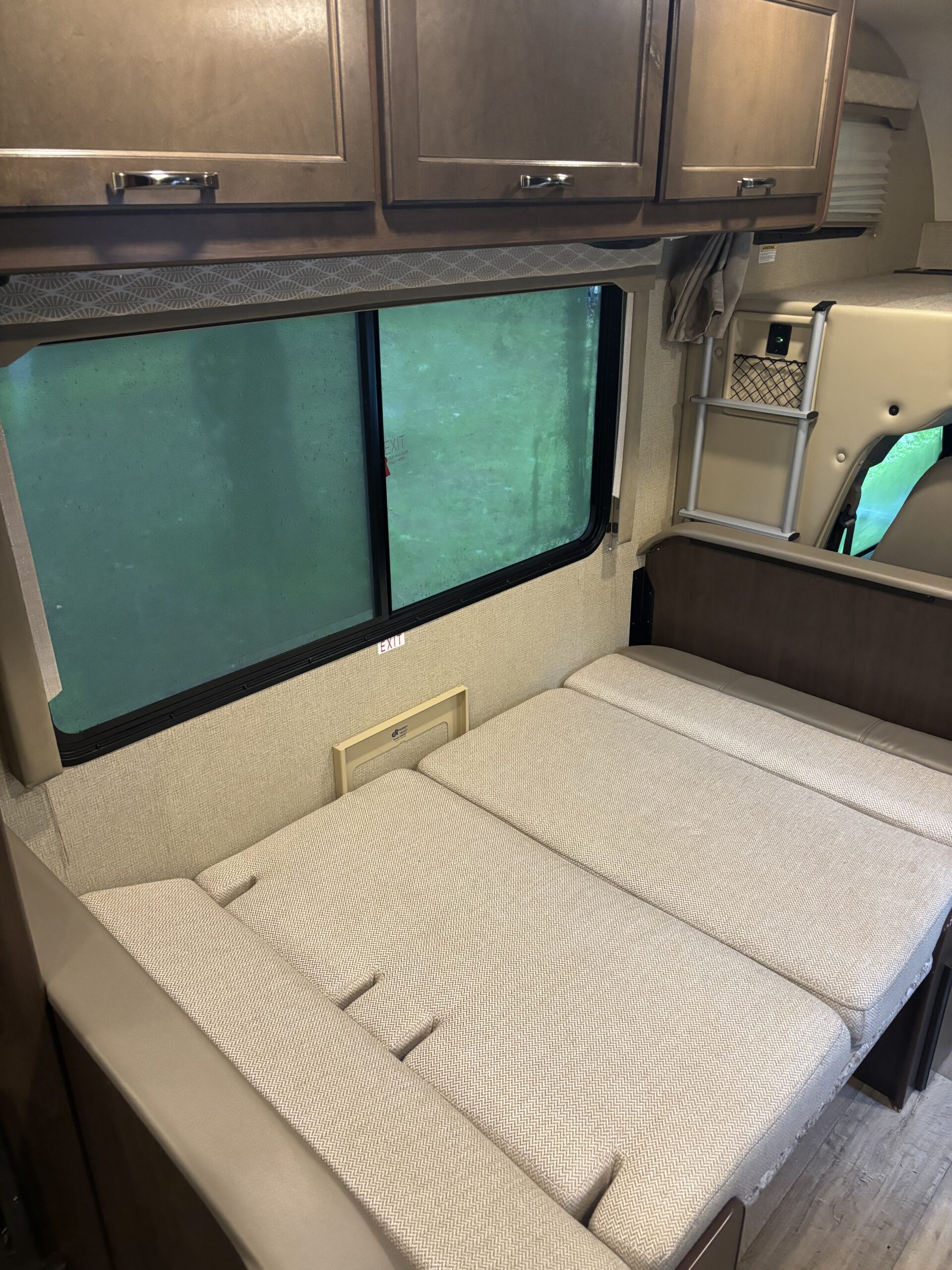 RV rental: RV interior showing wood cabinets, a dinette bed with light fabric, a large window, and a bunk ladder.. Thor Freedom Traveler 2019