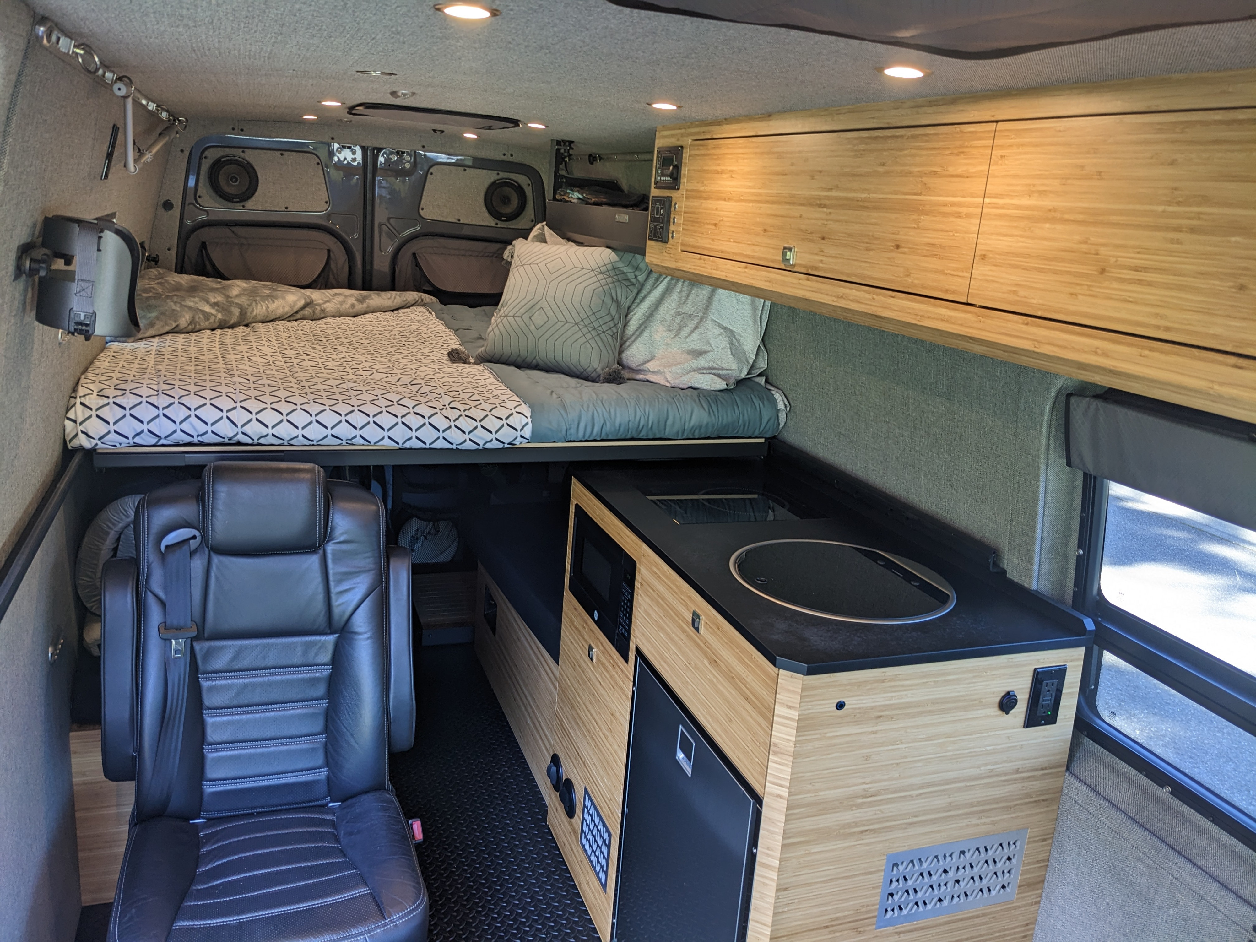 Inside a sleek RV rental: a comfy bed, functional kitchen with microwave & fridge, and plush seating for mobile adventures.. Mercedes Sprinter 2022