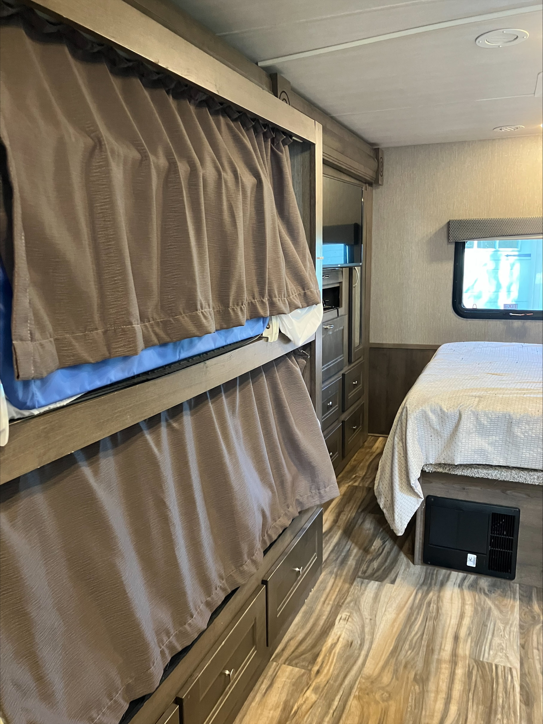 RV rental interior: cozy sleeping area with bunk beds (curtains for privacy), a main bed, and ample storage.. Nexus RV Triumph 2021