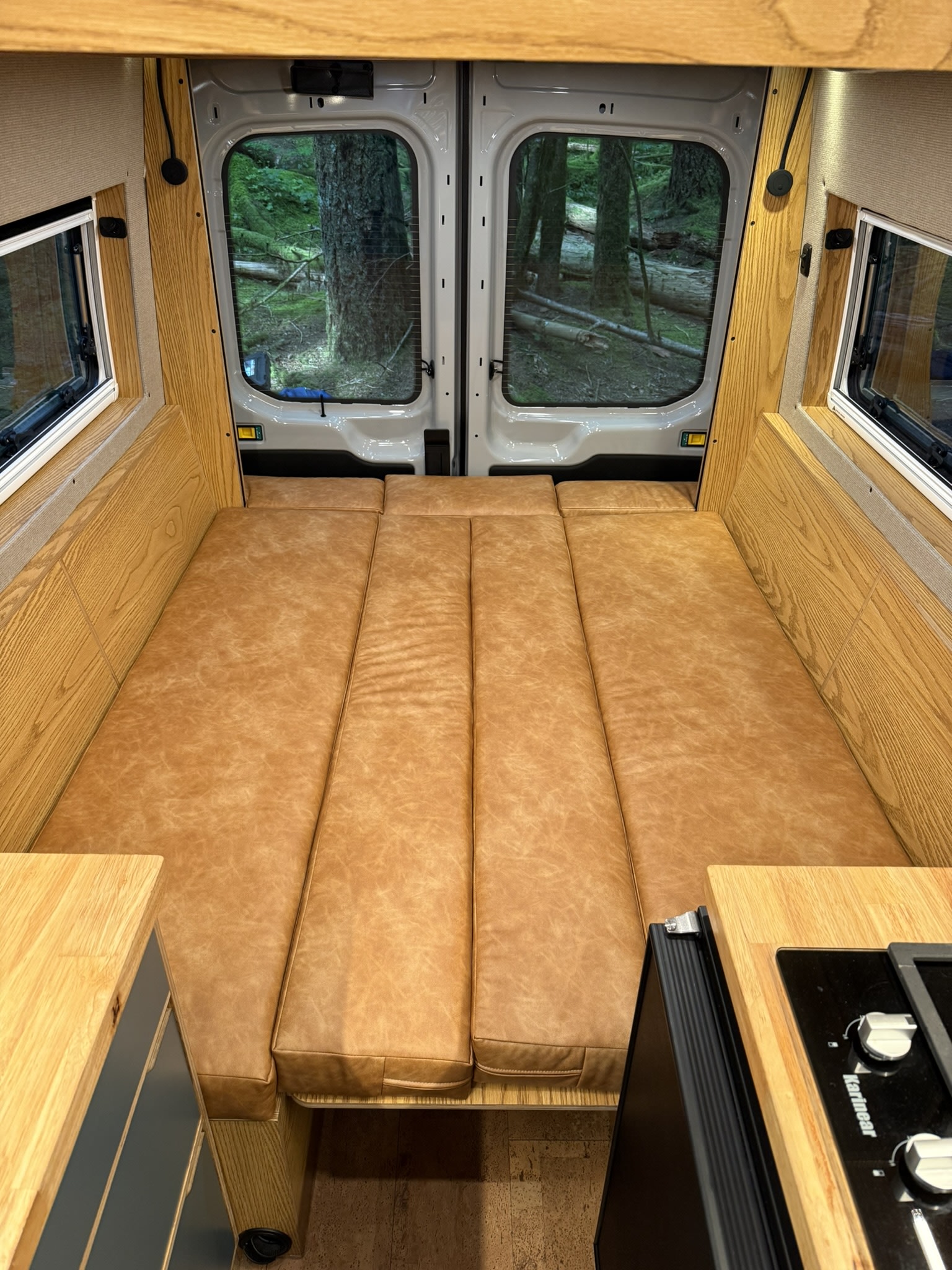 RV rental: This van conversion offers a flexible bed layout, warm wood interior, and scenic forest views for your adventure.. Ford Transit 2023