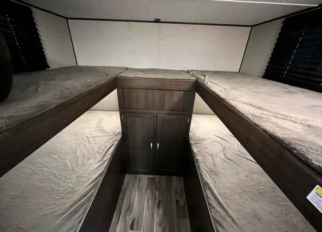 Cozy RV rental bunk beds. This RV interior features a four-bed sleeping area with two upper and two lower bunks, ideal for families.. Keystone RV Springdale 2019