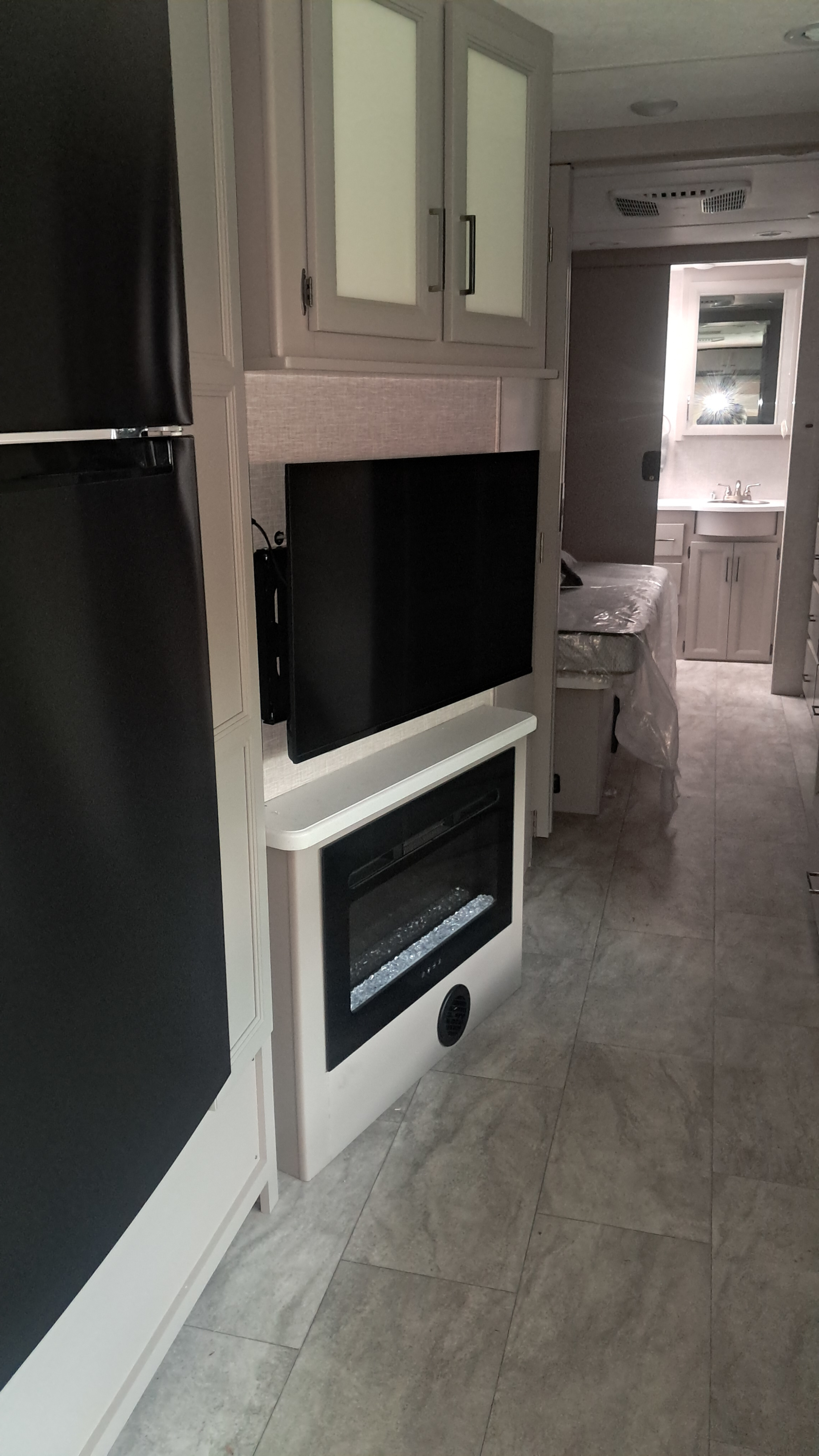 Modern RV rental interior showing a kitchen, living area with TV & fireplace, bedroom with covered bed, and bathroom.. Thor Windsport 35M 2025