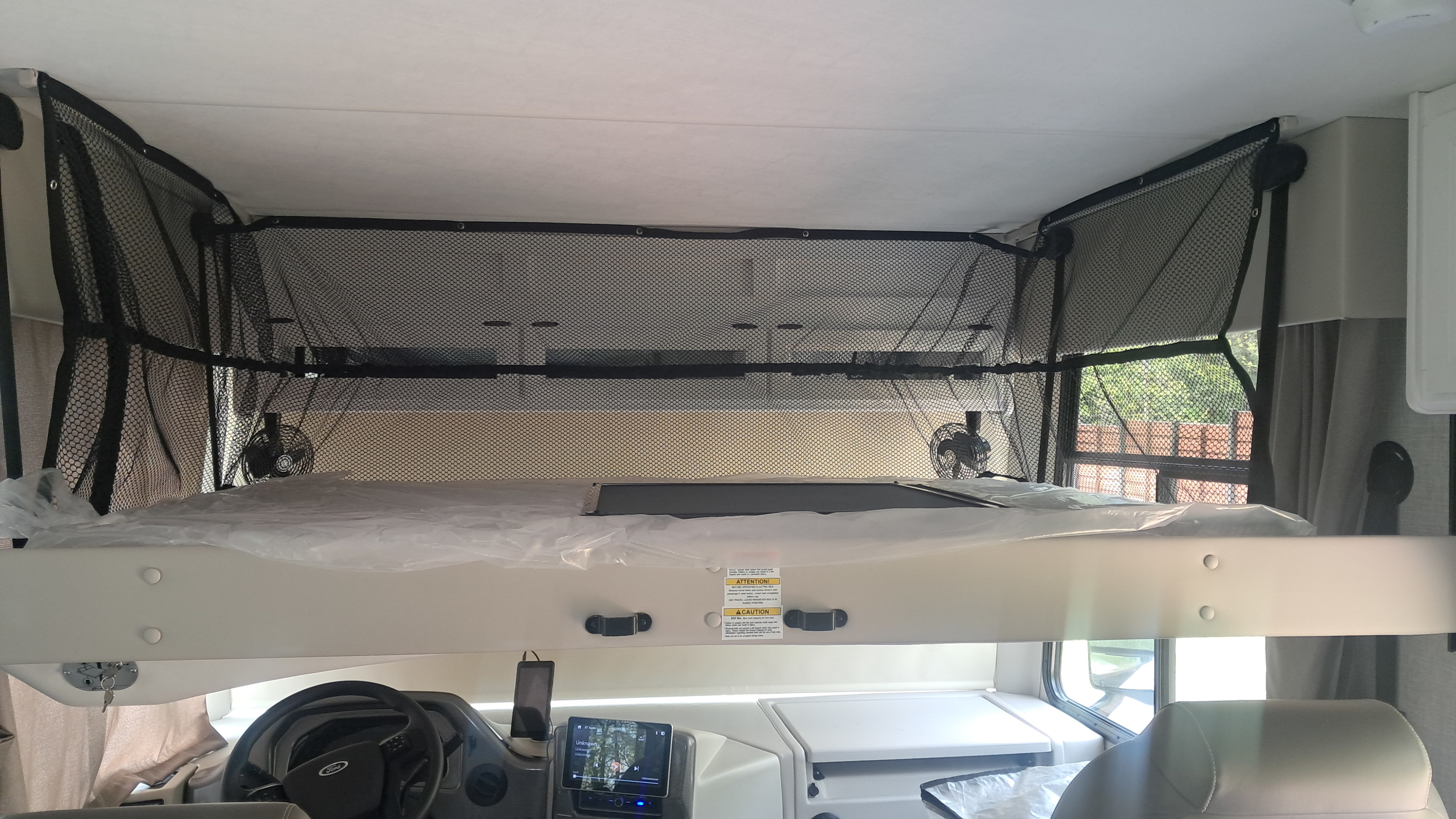Inside an RV rental: a spacious cabover bunk with a safety net & fans, perfect for extra sleeping space.. Thor Windsport 35M 2025