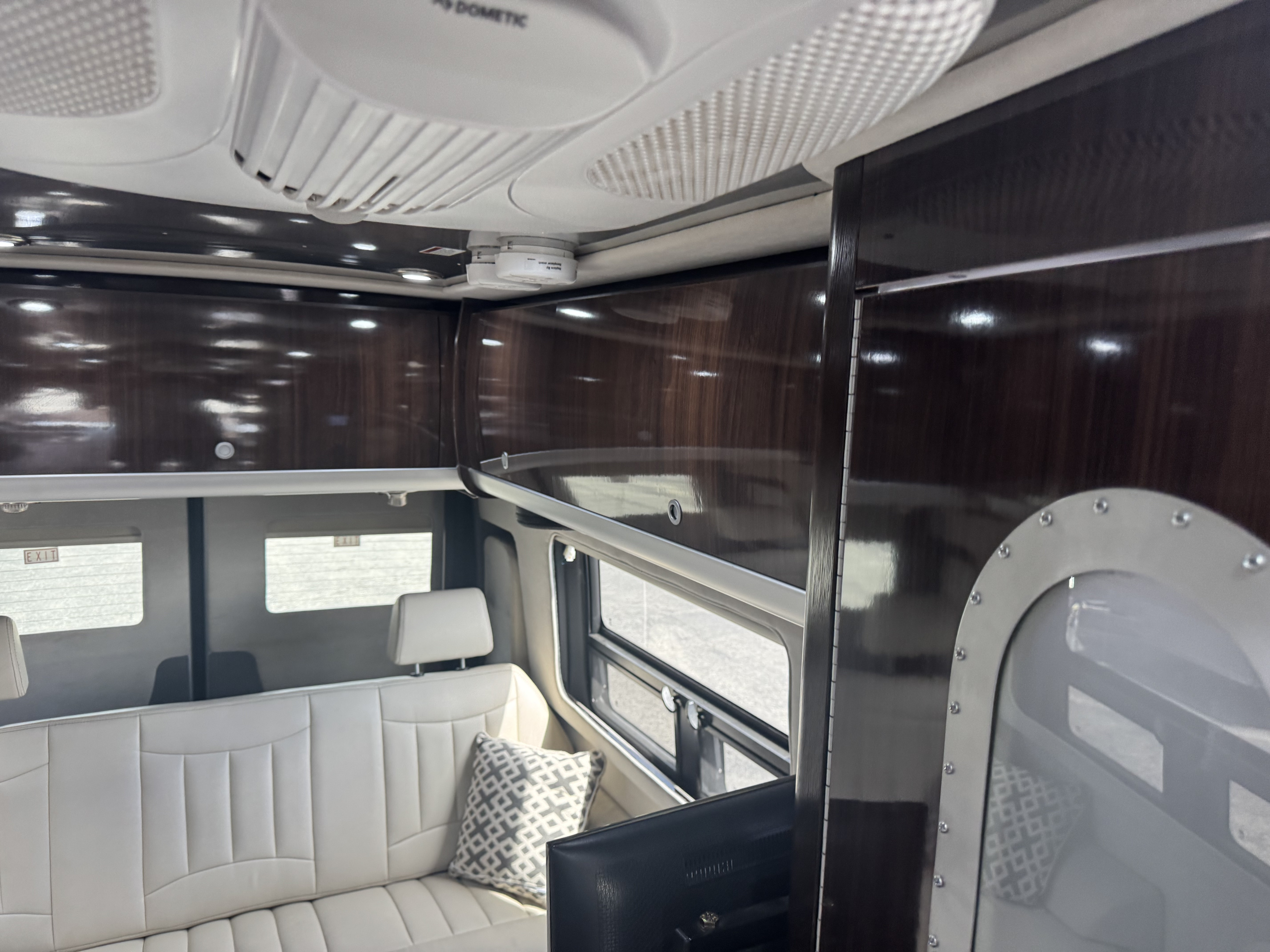 Spacious rv rental interior featuring a white sofa, sleek wood cabinets, and overhead climate control for comfort.. Airstream Interstate 2017