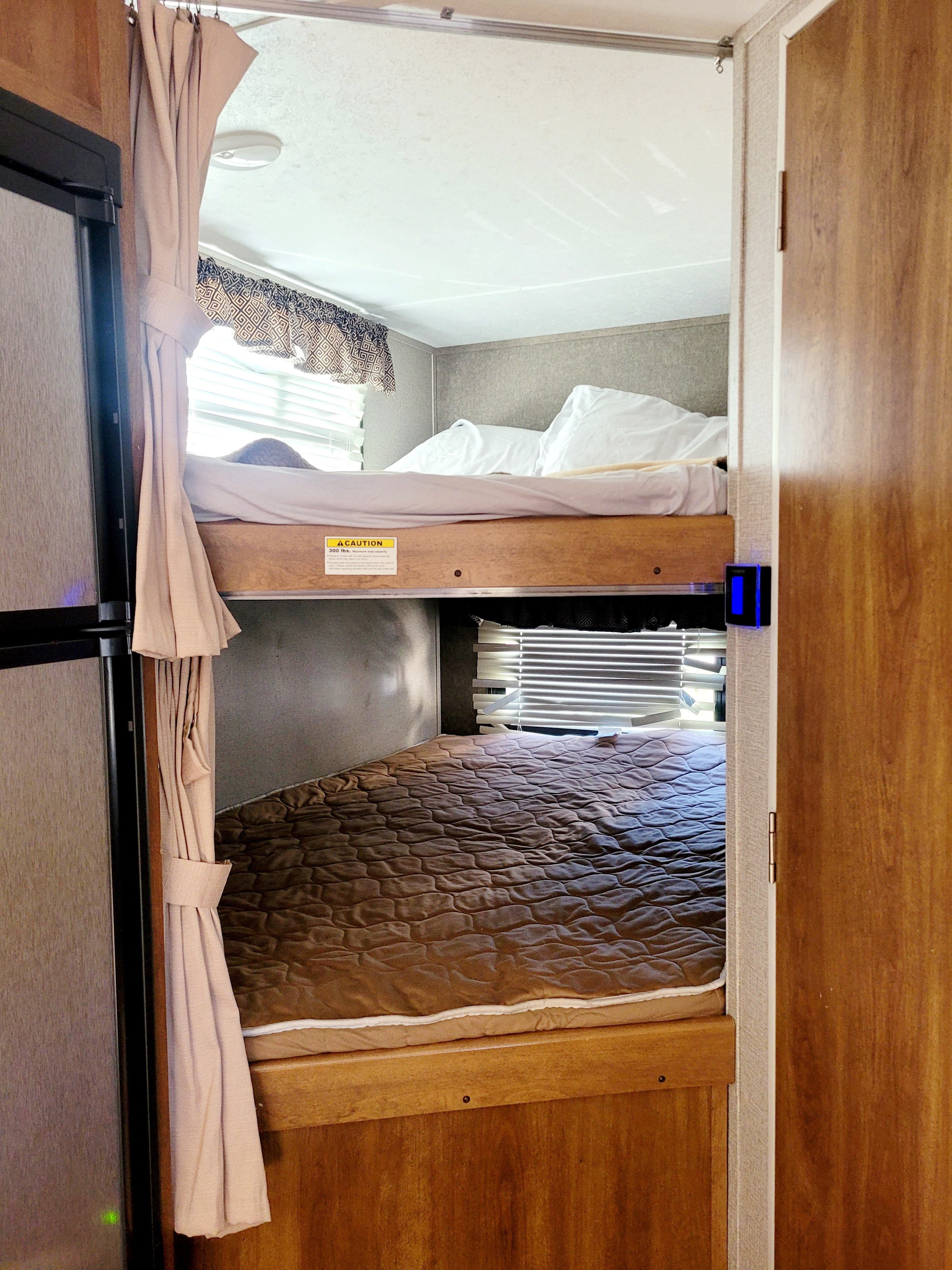 Cozy RV rental interior featuring twin bunk beds with bedding and privacy curtains.. Keystone RV Springdale 2017