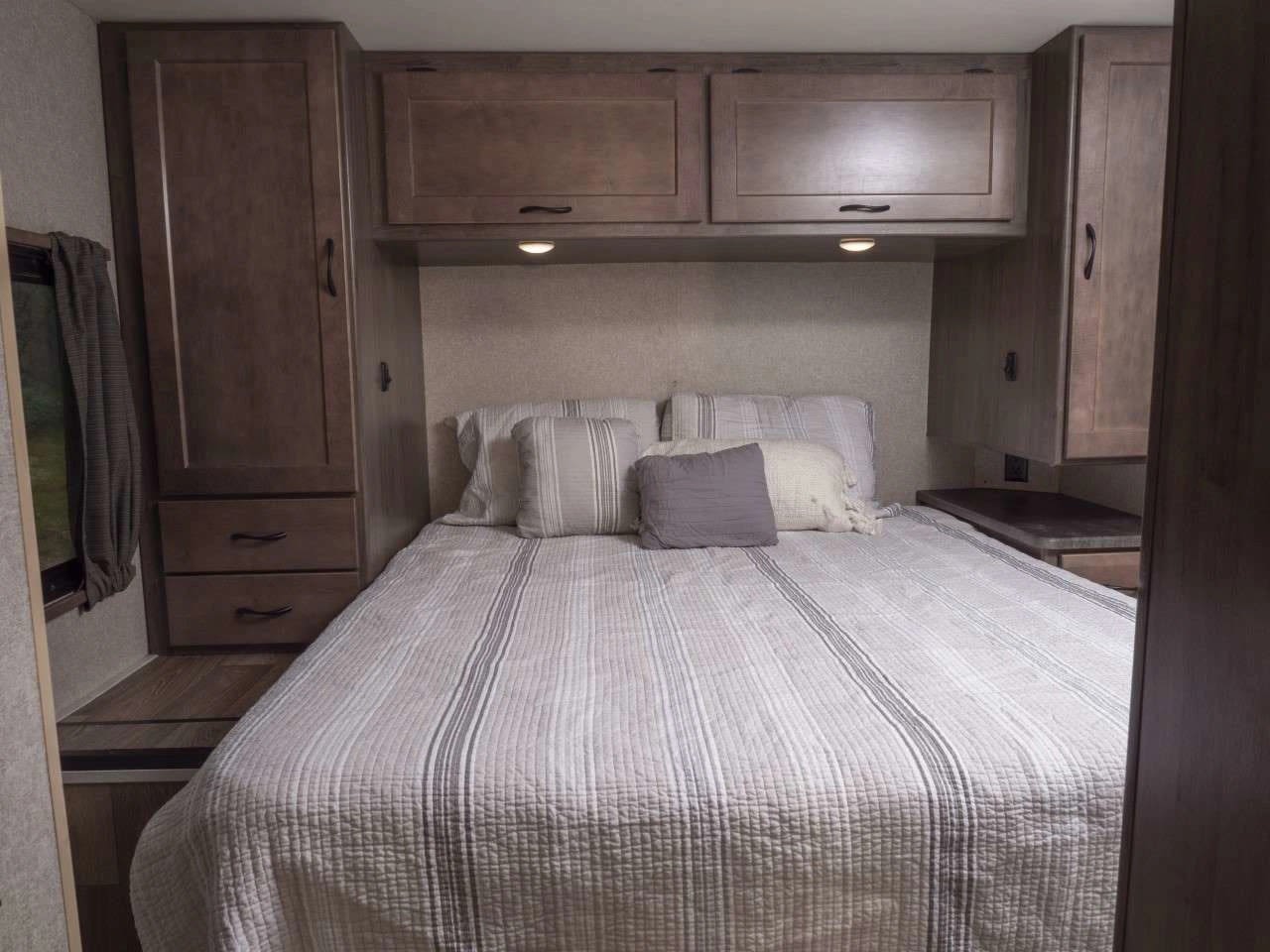 Spacious and comfortable RV rental bedroom interior with queen bed, overhead cabinets, and built-in storage.. Winnebago Minnie Winnie 2020