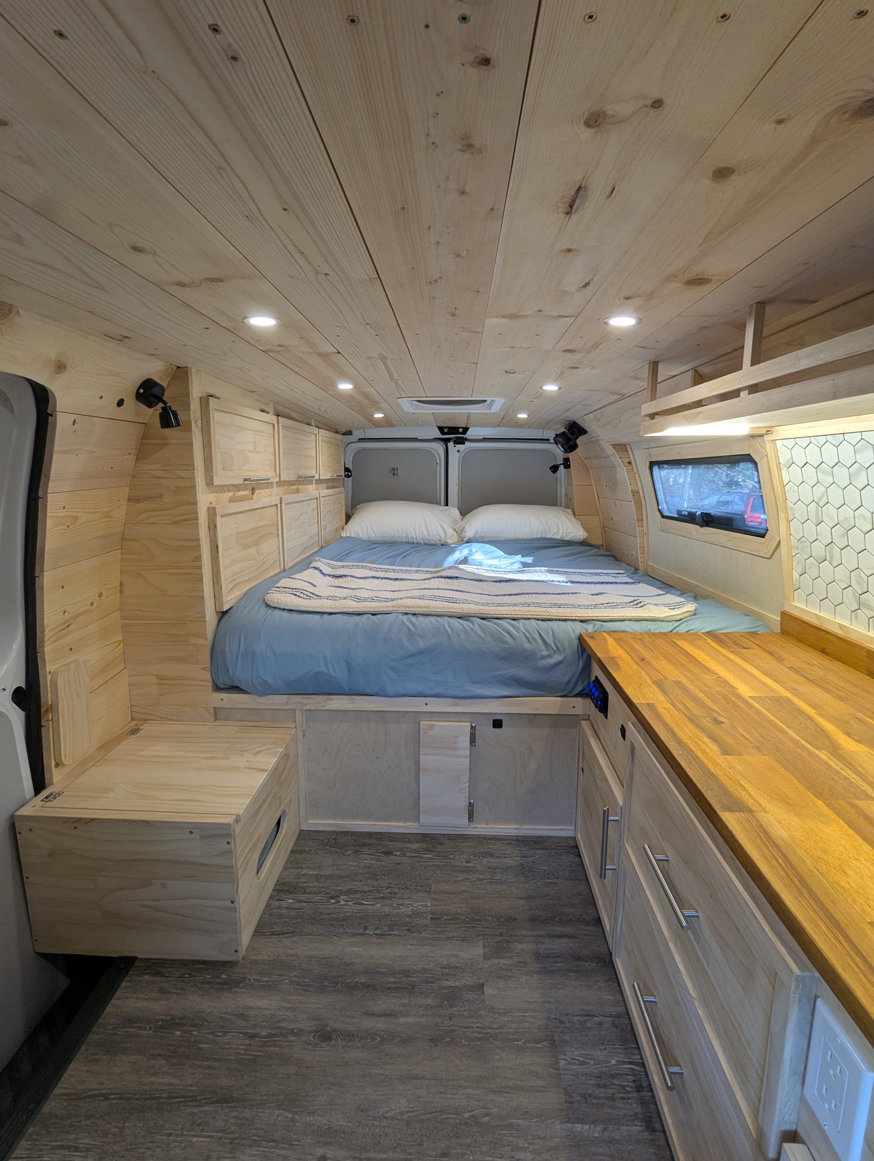 Step into this cozy RV rental's wooden interior, showcasing a comfortable bed, overhead storage, and counter space.. Gmc Savanna 2016