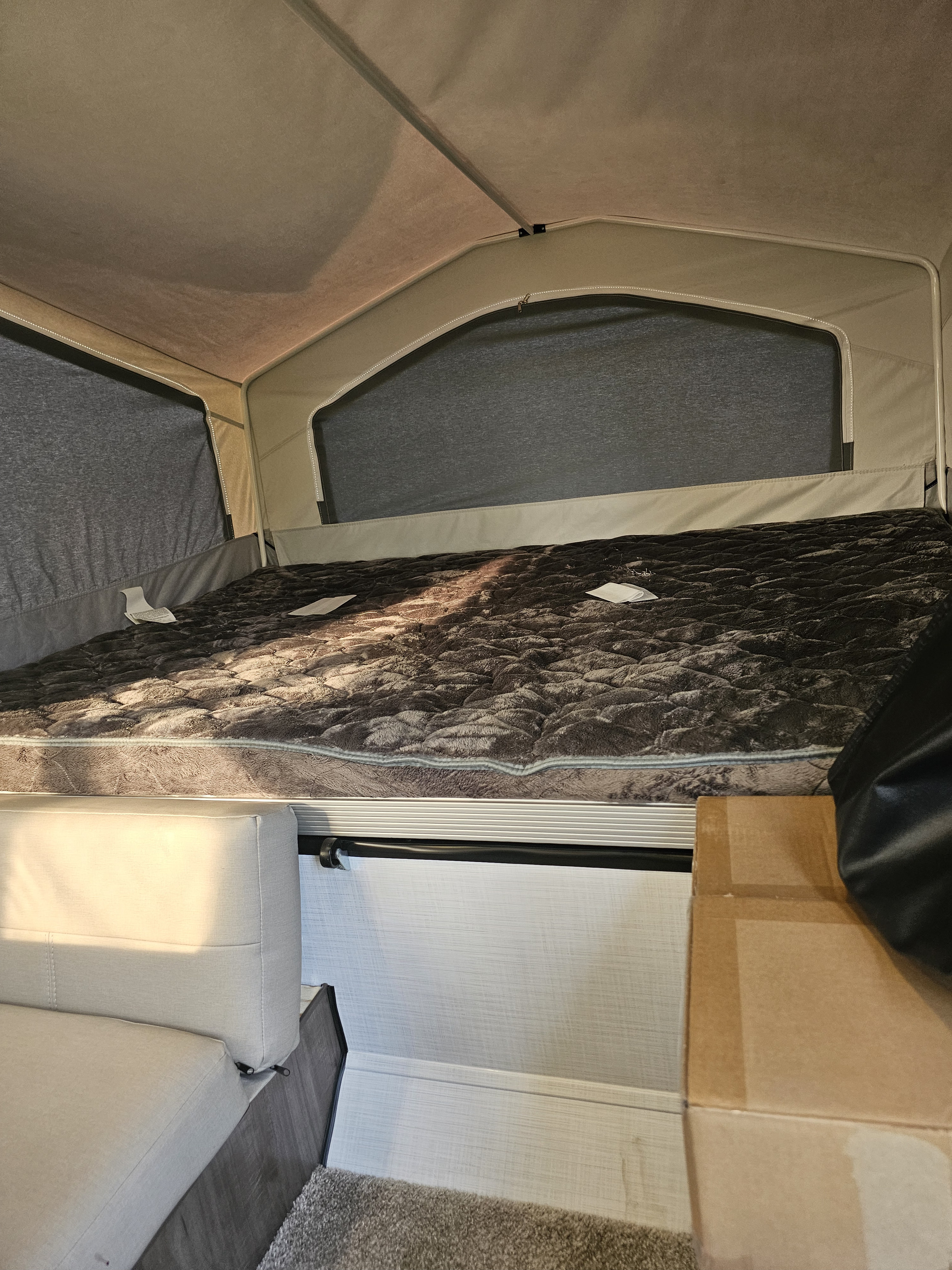 Cozy RV rental interior featuring a large pop-up bed, with an inviting sofa below, perfect for camping.. Forest River Rockwood LTD 2024
