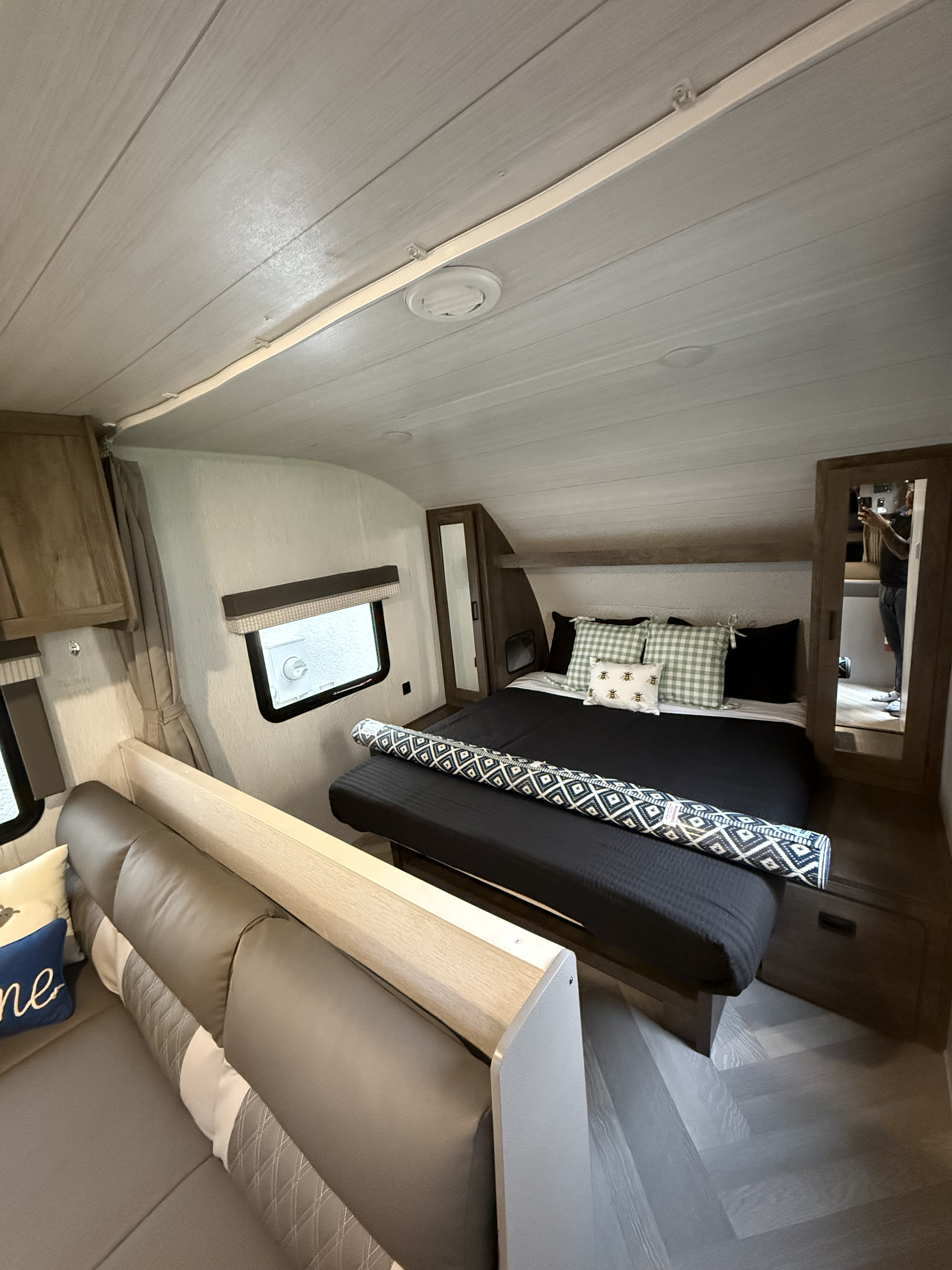 Inside this RV rental: a compact bedroom with a black bed, patterned pillows, and an adjacent grey sofa.. Forest River Salem Cruise Lite 2022