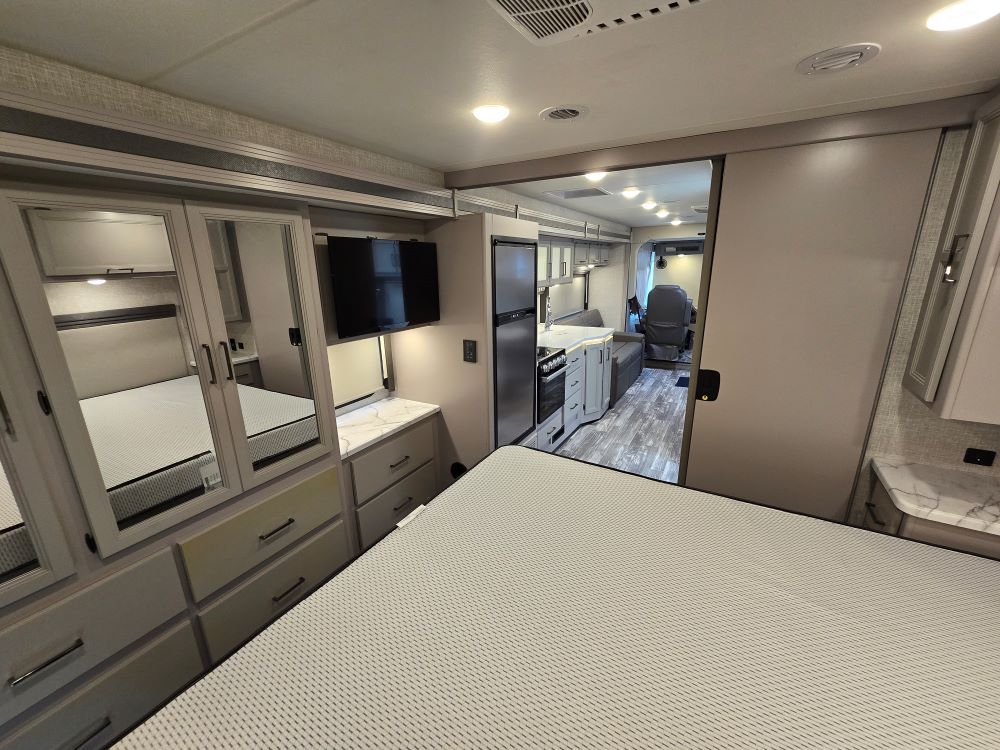 This RV rental offers a well-appointed bedroom with mirrored storage & TV, opening to a full kitchen, living, and lounge area.. Thor Hurricane 29M 2022