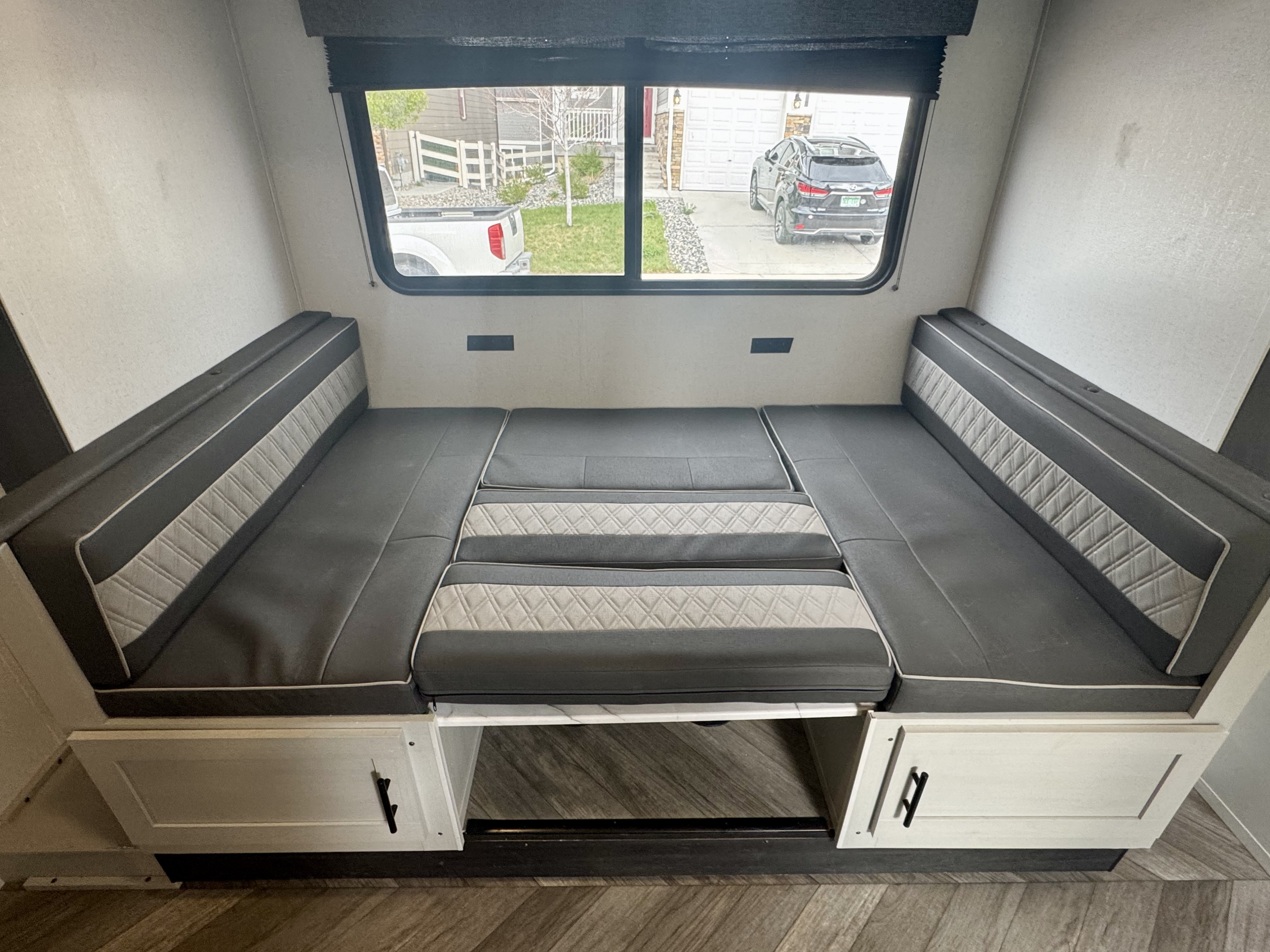 Spacious RV rental features a flexible dinette with gray upholstered cushions, converting to a bed, with storage and window views.. Forest River Salem FSX 2022