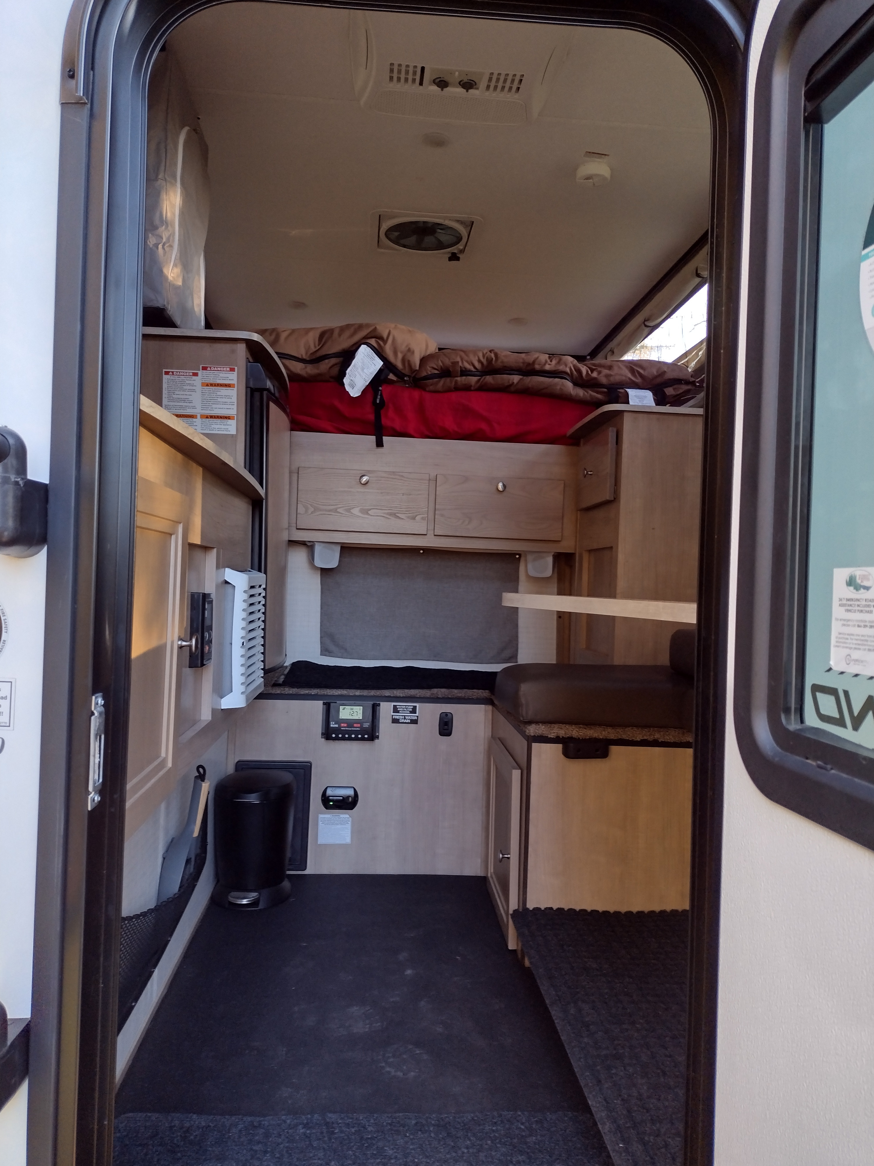 This RV rental interior offers a compact living space with a bed, dinette, and functional amenities.. Palomino Backpack Edition 2023