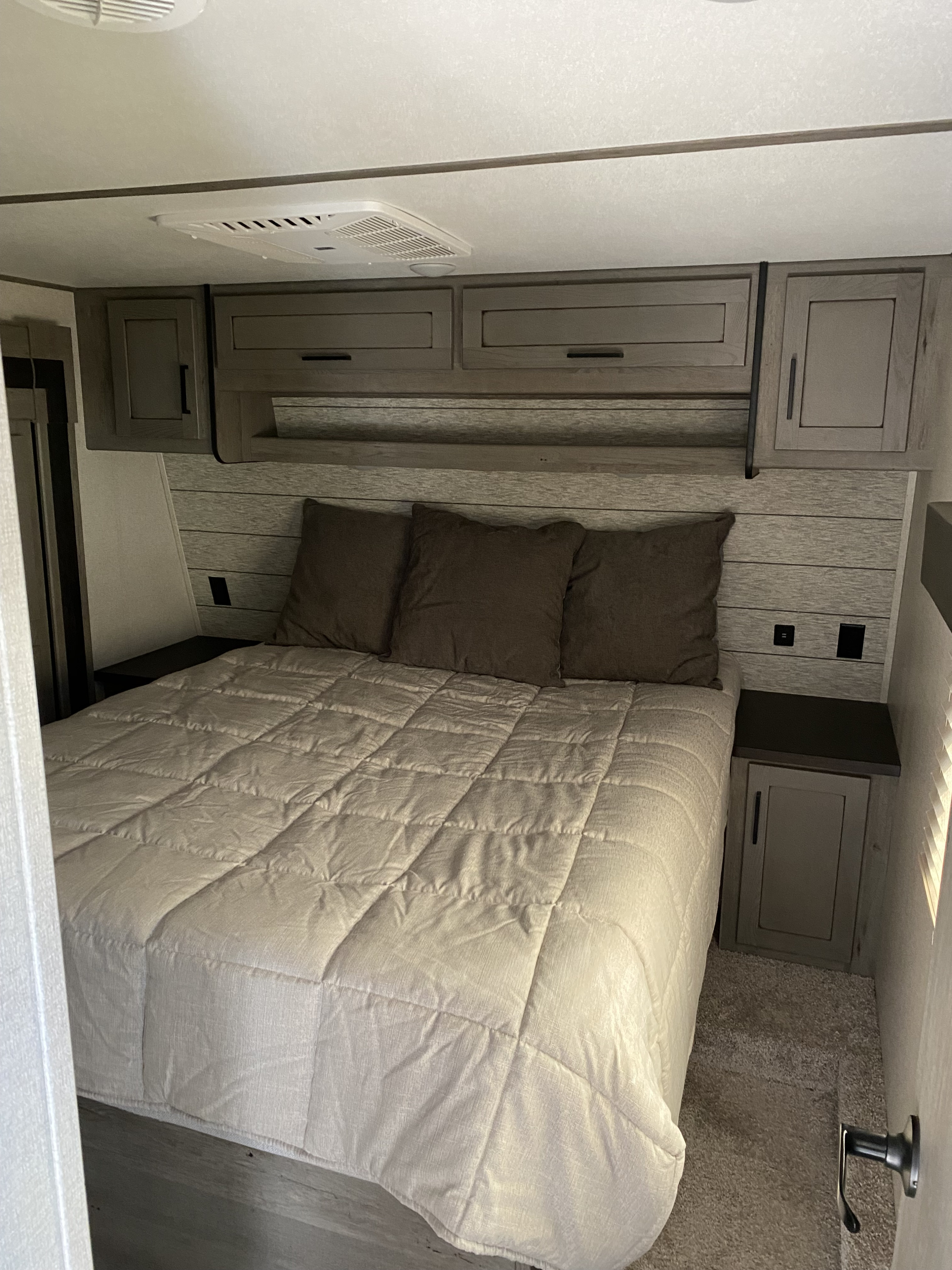 Comfortable RV rental bedroom featuring a full bed, overhead cabinetry, and side tables for a compact, cozy stay.. Keystone Carbon 2020