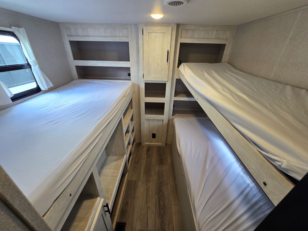 RV rental interior: A bright bunkhouse features two sets of beds, integrated storage, and a window, perfect for families.. Shasta Oasis 31OK 2024