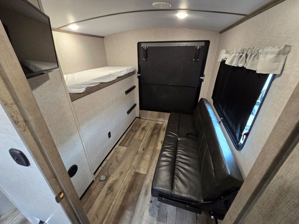 RV rental interior: bunk beds, sofa, and rear ramp for gear access. A versatile space for adventure travel.. Keystone Outback 335CG 2021