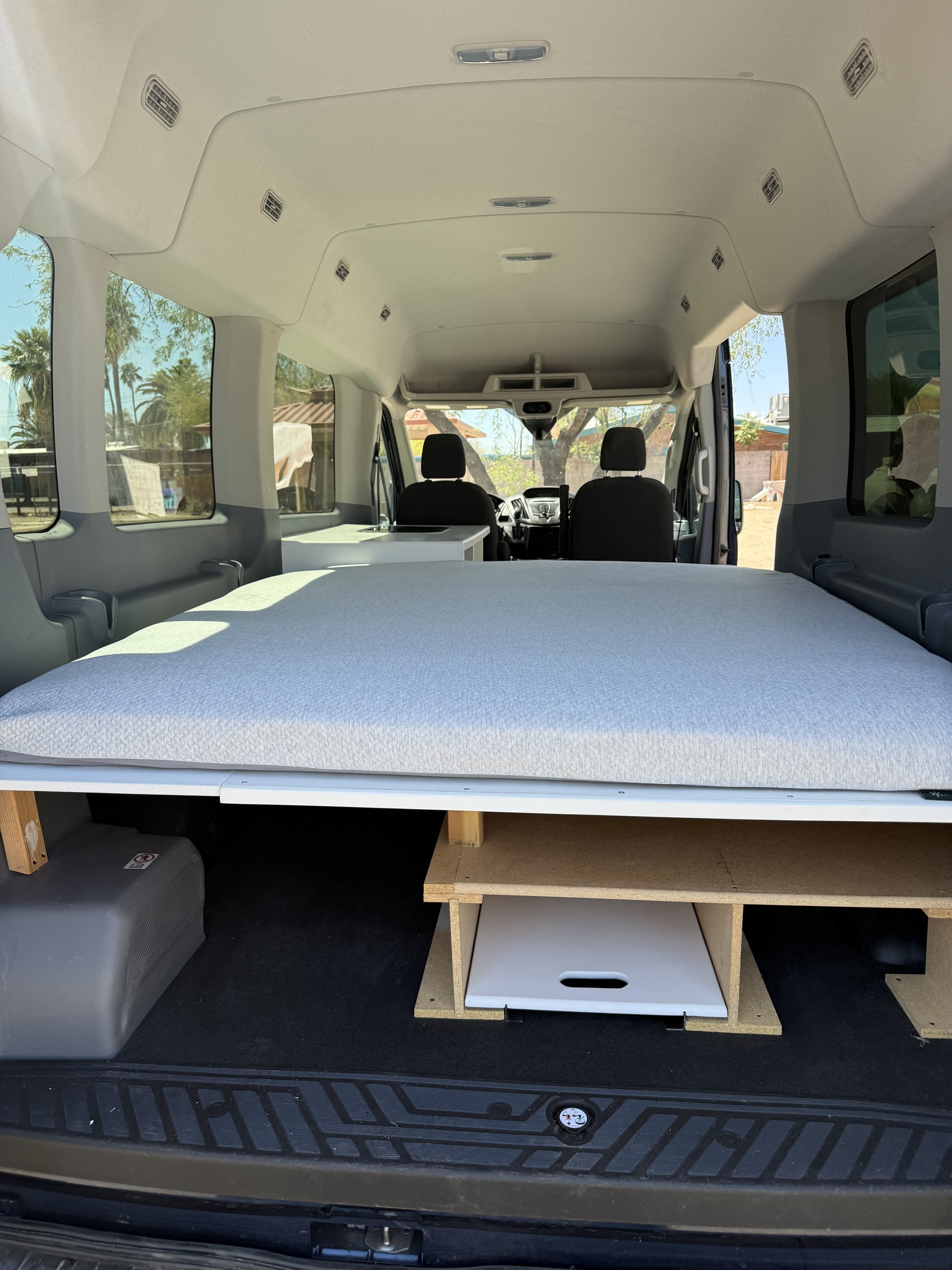 RV rental: Campervan interior reveals a comfortable sleeping area on a raised storage platform. Front cabin visible.. Ford Transit 3500 2015