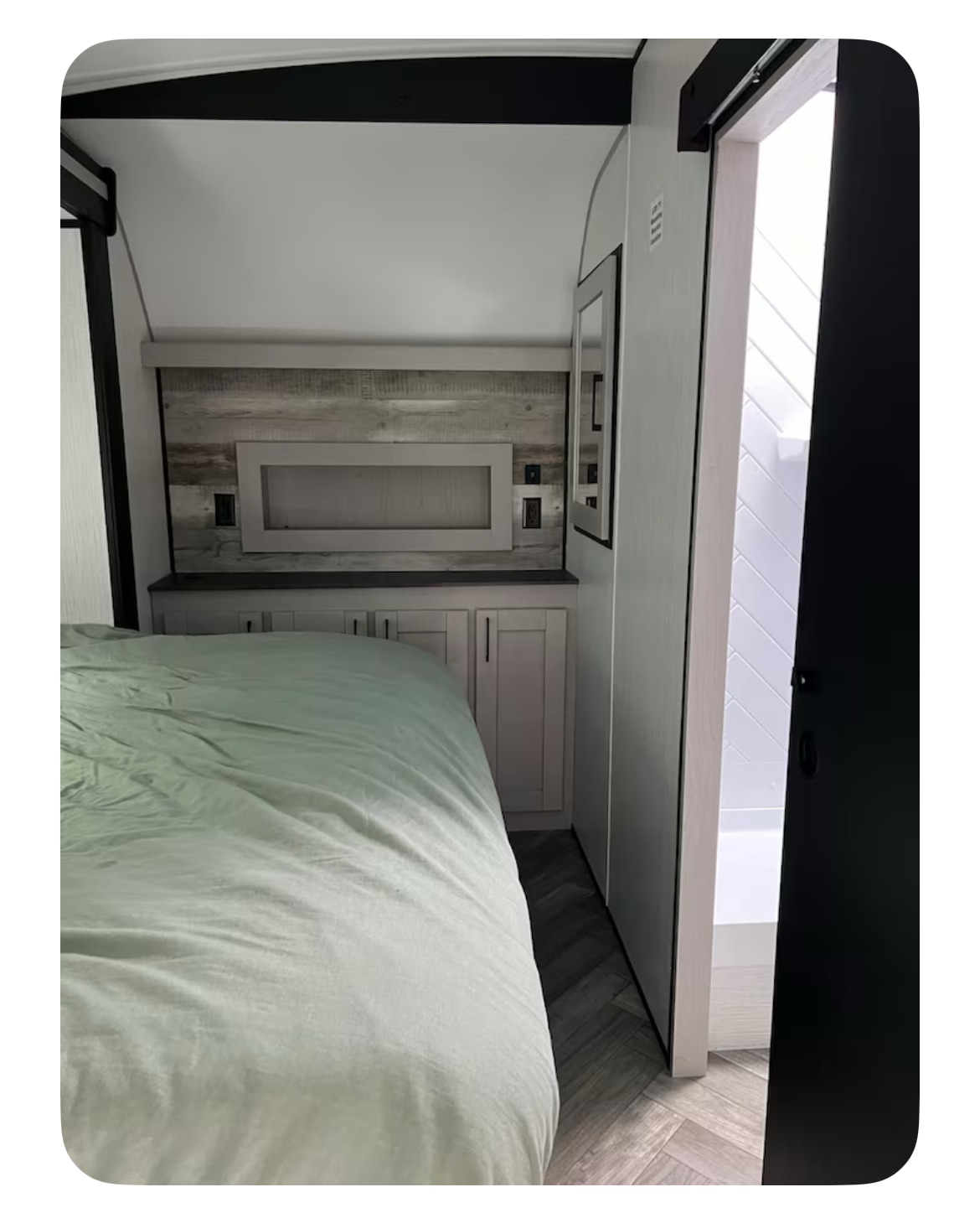 Inside this modern **rv rental**: a cozy bedroom featuring a light green bed, built-in storage, and shower access.. Heartland RVs Torque Toy Hauler 2022