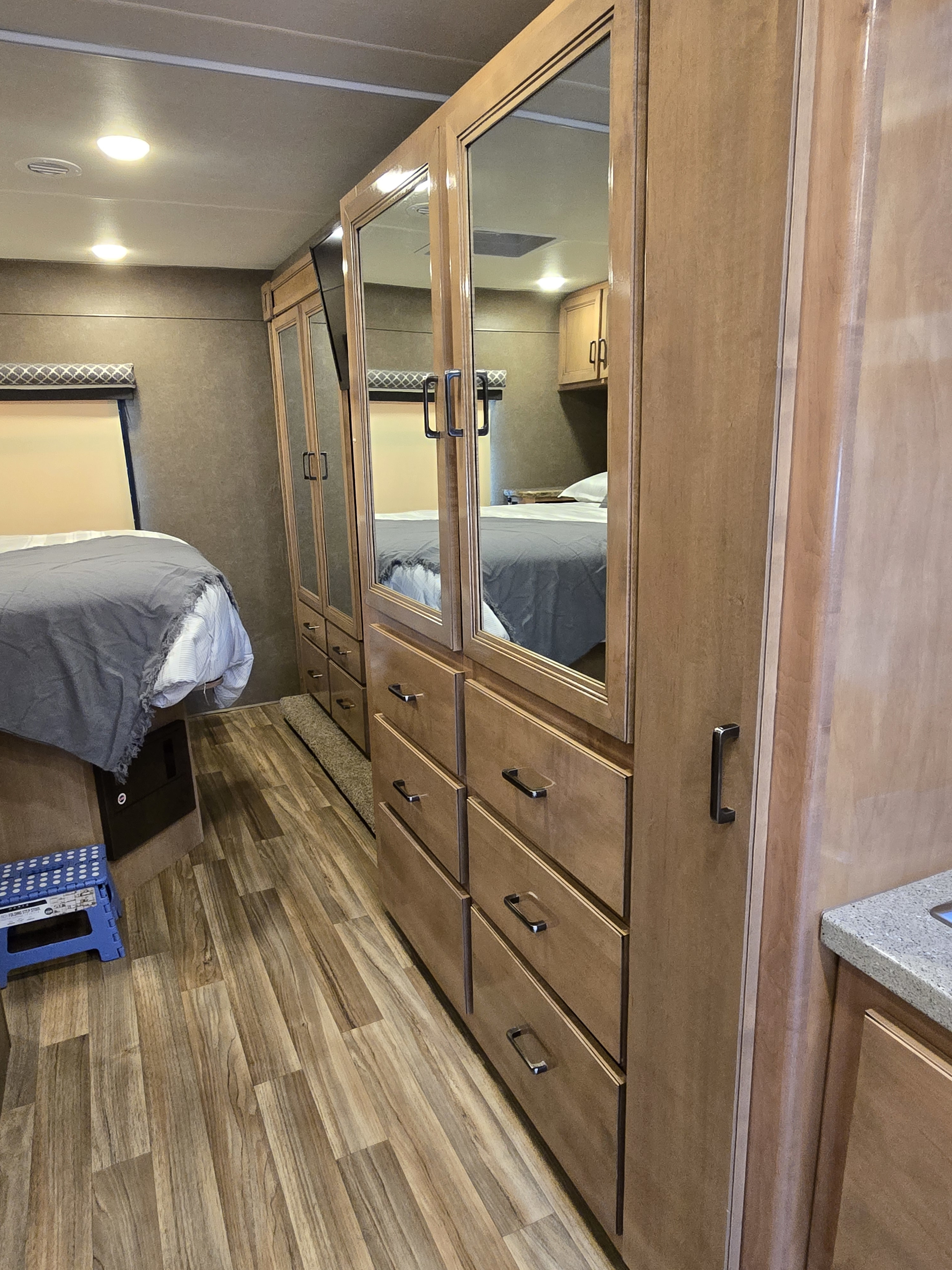Spacious RV rental bedroom with mirrored wardrobe, comfortable bed, and wood flooring, perfect for travel.. Thor Quantum 2019