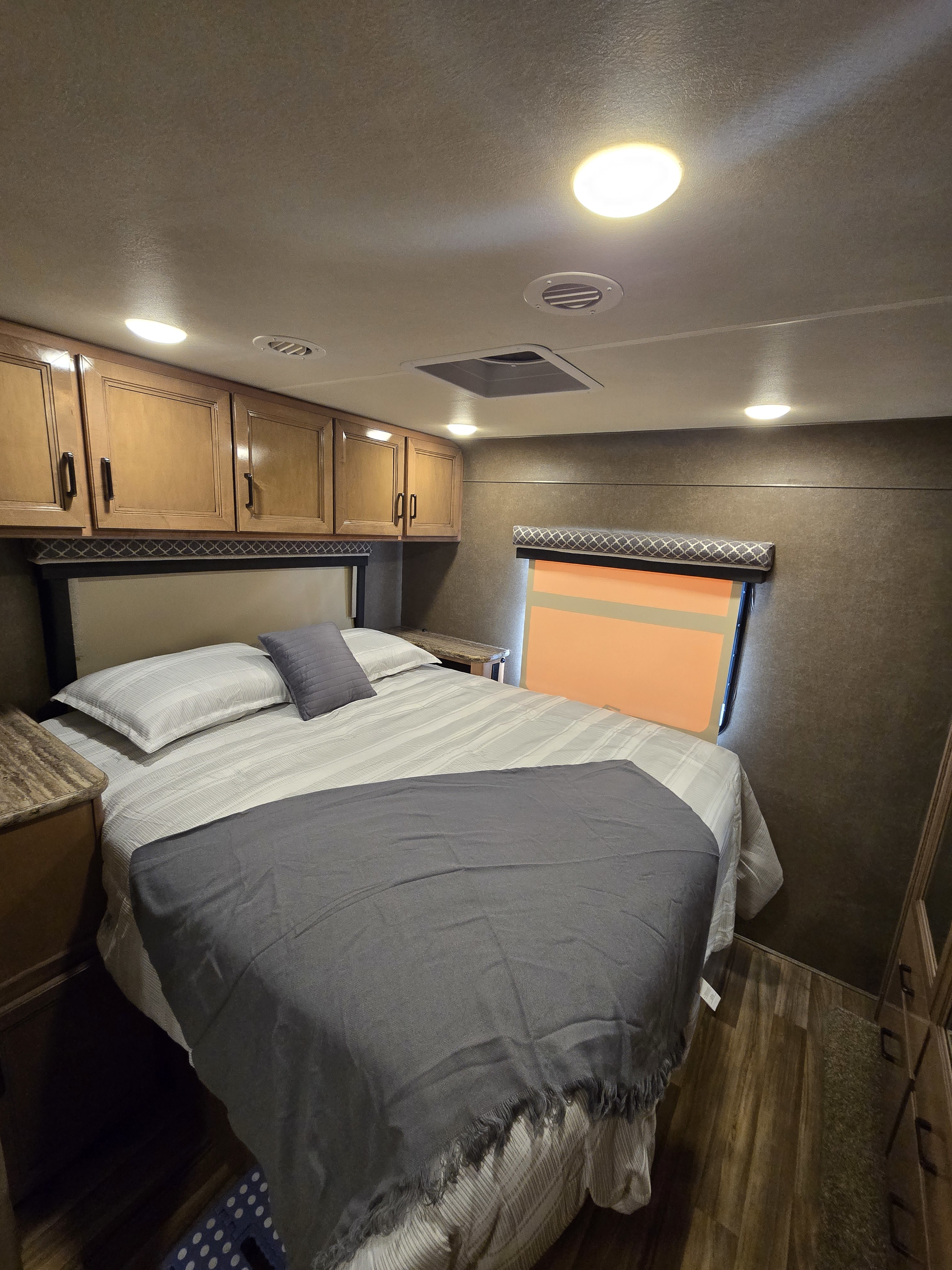 Cozy rv rental bedroom with a comfy bed, overhead cabinets, and a window. Ideal for trips!. Thor Quantum 2019