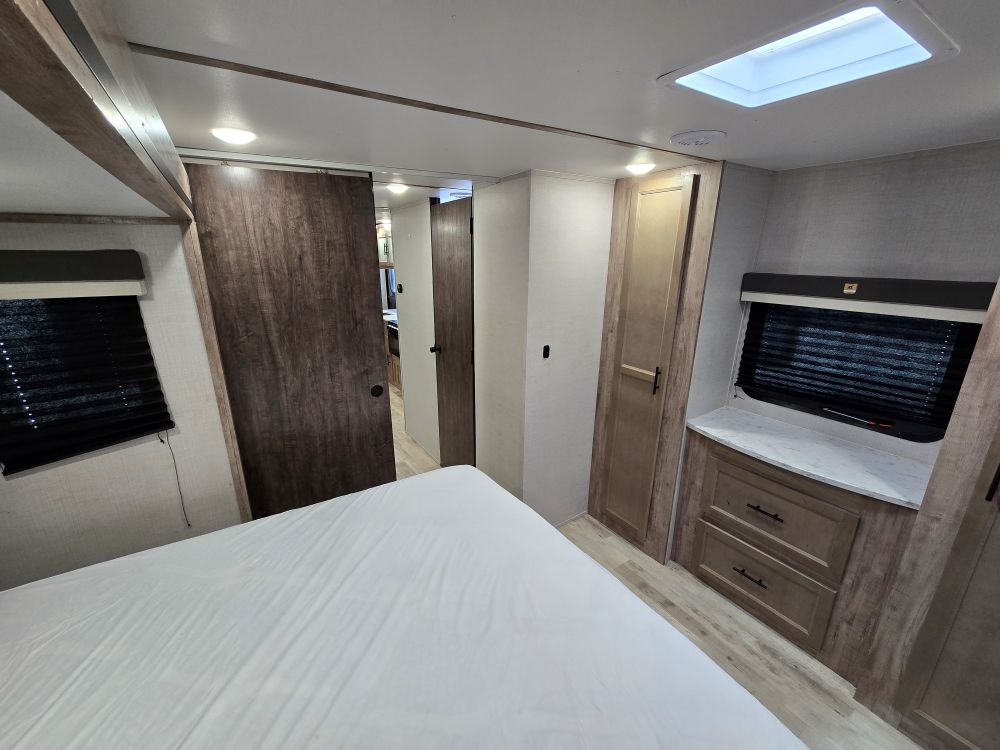 Spacious RV rental bedroom with modern wood finishes, comfortable bed, and ample storage for your travels.. Gulf Stream Kingsport 33DBDB 2024