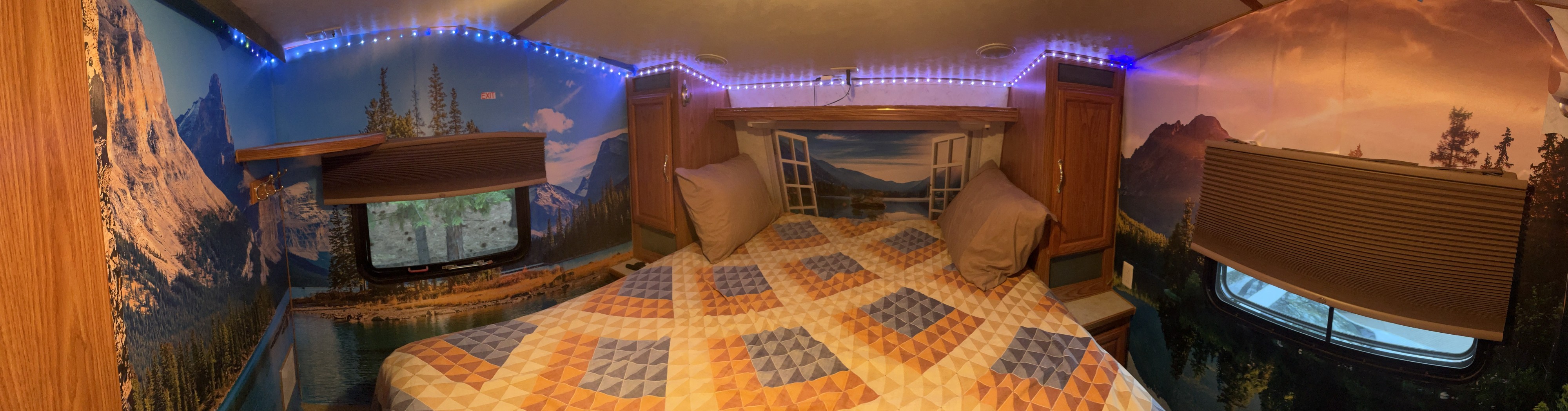 Customized RV rental bedroom with scenic nature murals, a comfy bed, and blue ambient lights.. Komfort Komfort Fifth Wheel 2001