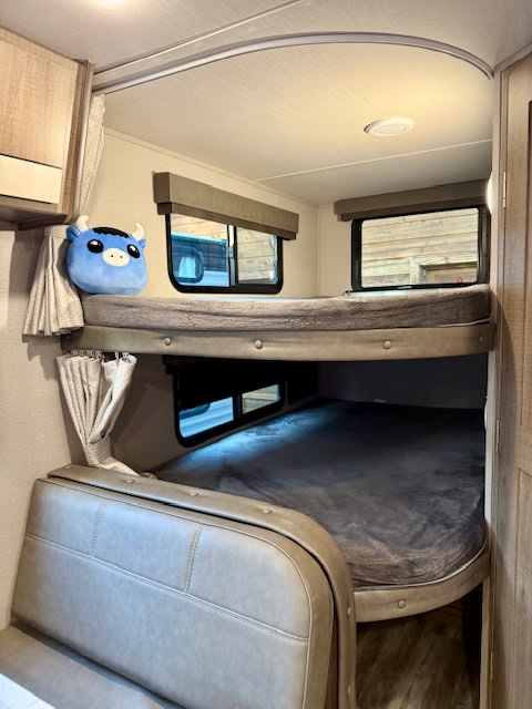 Cozy RV rental featuring comfortable bunk beds and a built-in dinette, ideal for family adventures.. Grand Design Imagine 2021