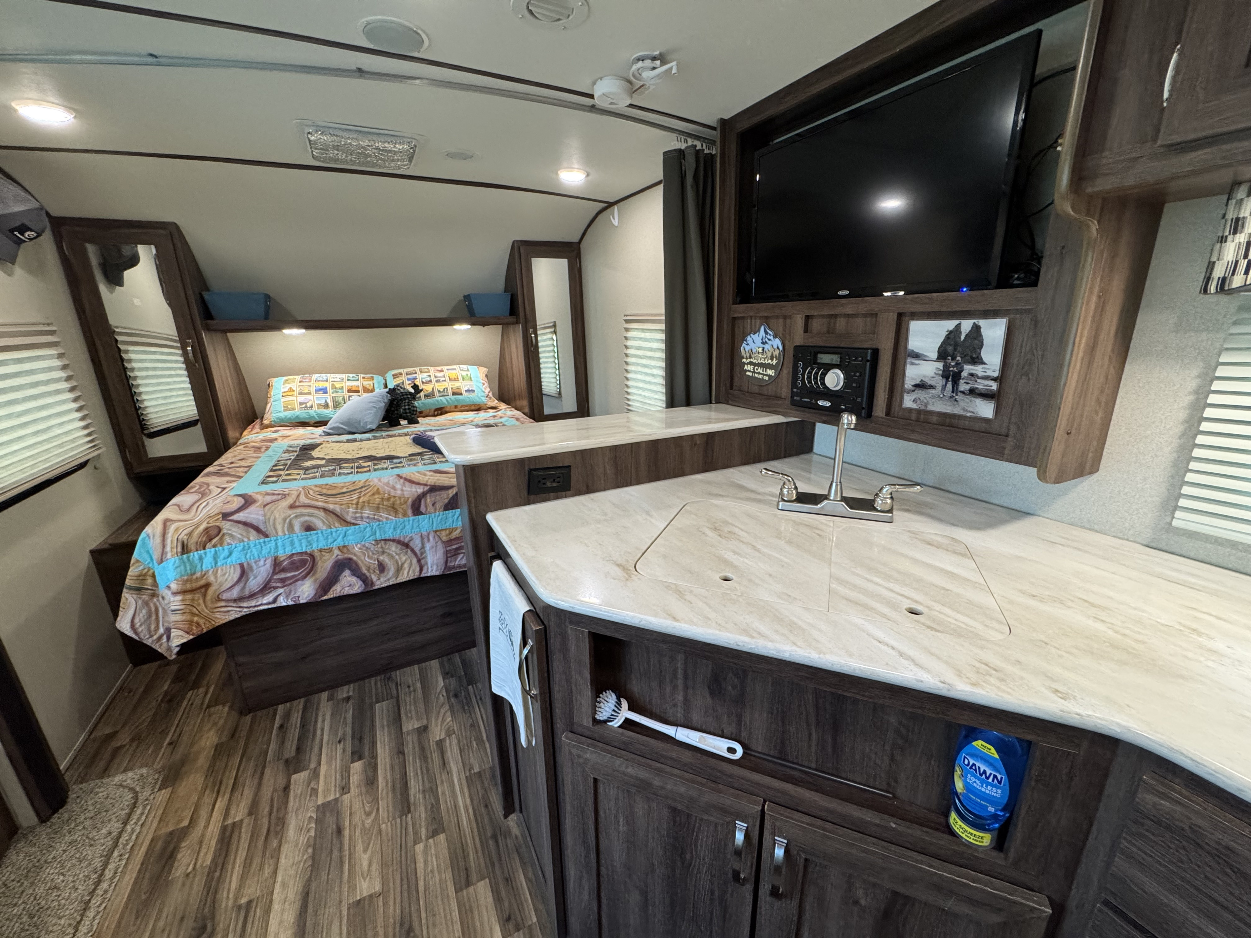 Cozy rv rental interior: bedroom, compact kitchen with sink, and entertainment system.. Evergreen RV iGO 2016