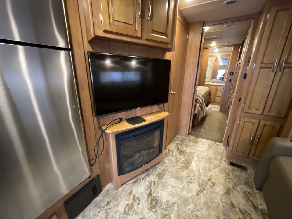Inside your next RV rental: a modern kitchen with fridge, living area with TV & fireplace, and a cozy bedroom.. Coachmen Mirada 2016