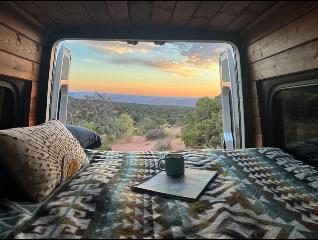 Scenic RV rental adventure: cozy bed setup with a stunning sunset over the landscape, seen from inside the van.. Mercedes Sprinter 2008
