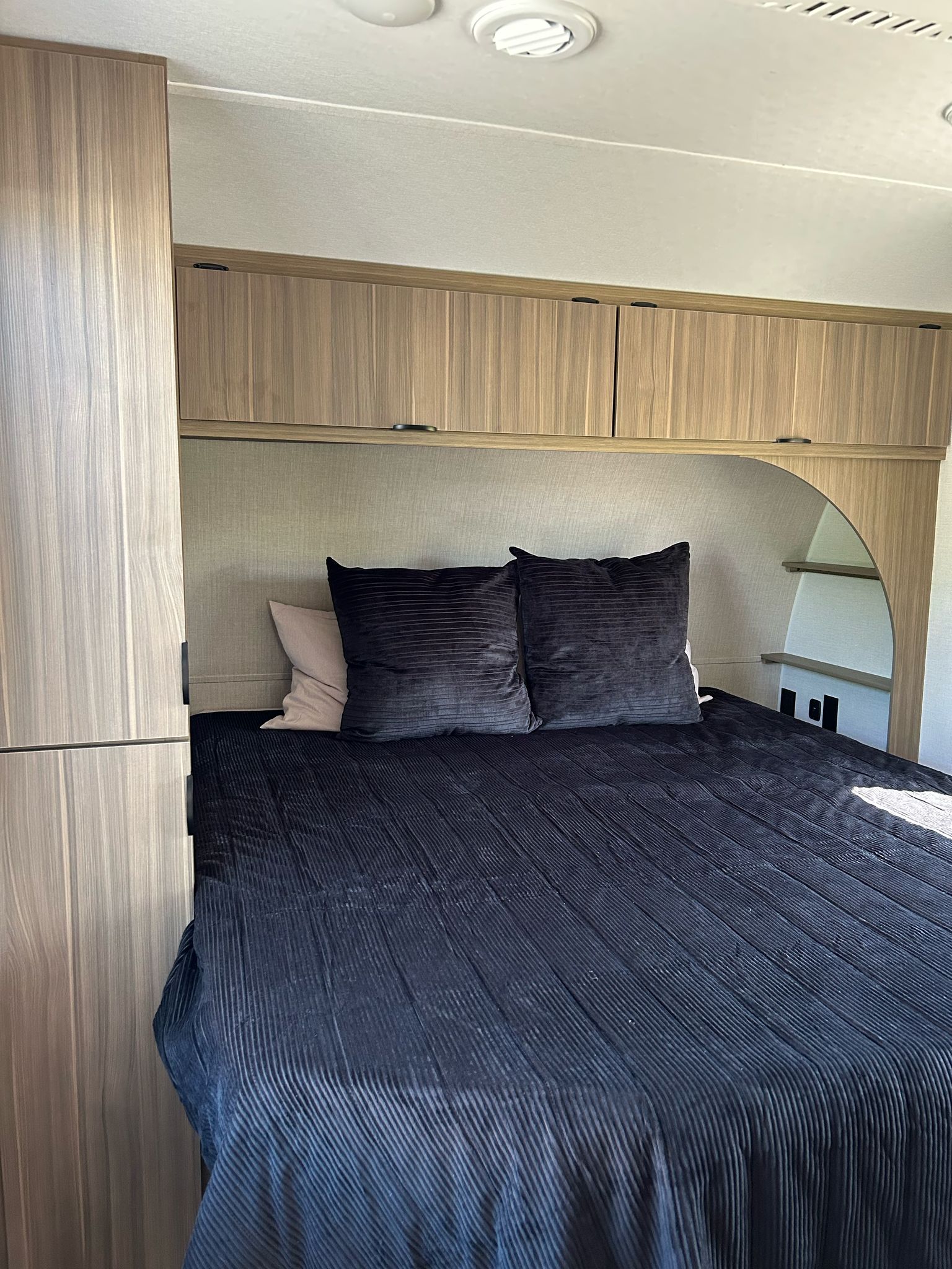 Cozy RV rental bedroom with a dark bed, wood cabinets, and built-in storage. Perfect for your next adventure.. Forest River RV 34VERANDA 2025