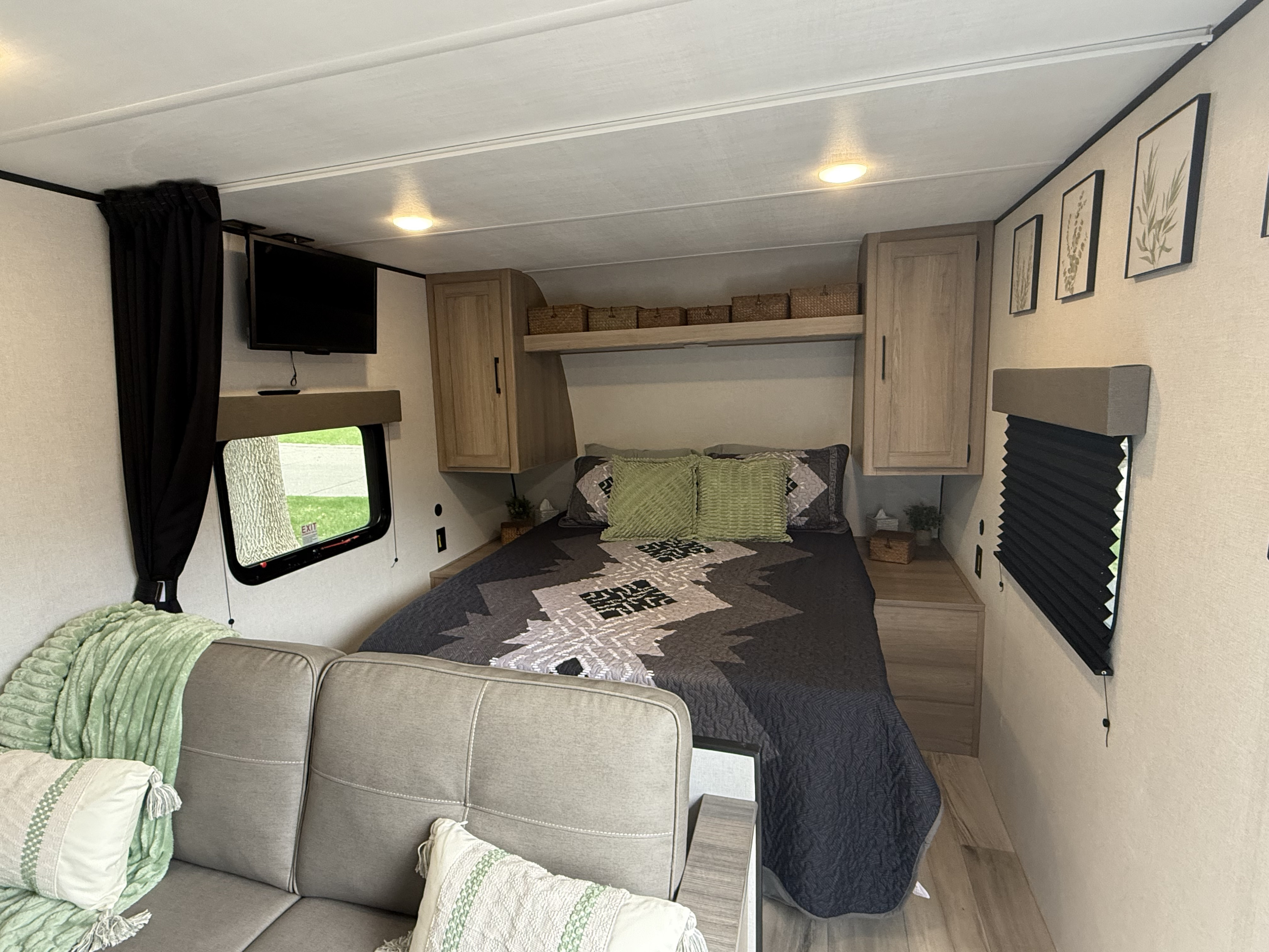 Cozy RV rental interior with bed, sofa, TV, and storage for comfortable travels.. Keystone RV 23B 2025