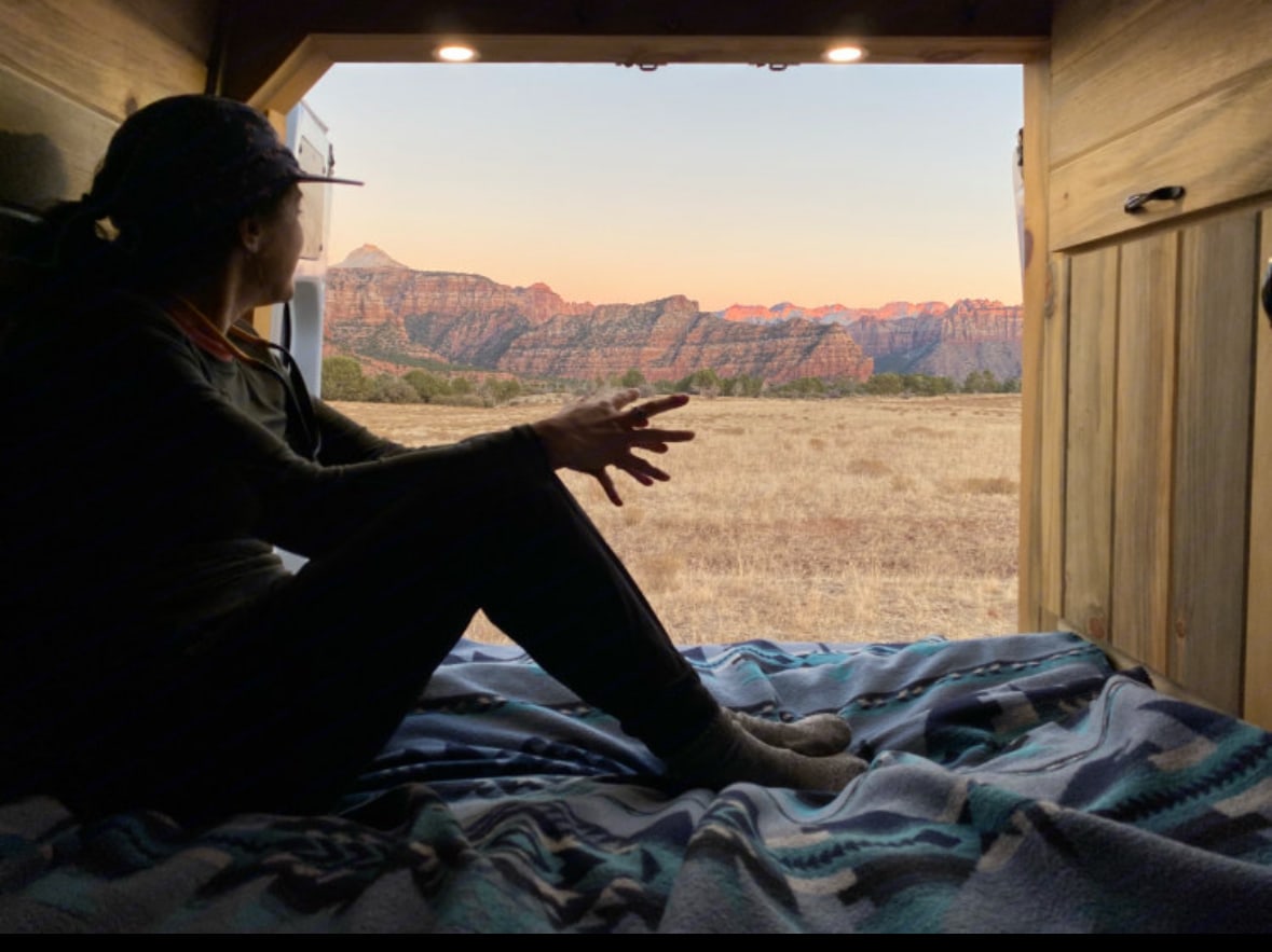 A person watches a red rock mountain sunset from their cozy **rv rental** van. Perfect view for a peaceful adventure.. Mercedes Sprinter 2011