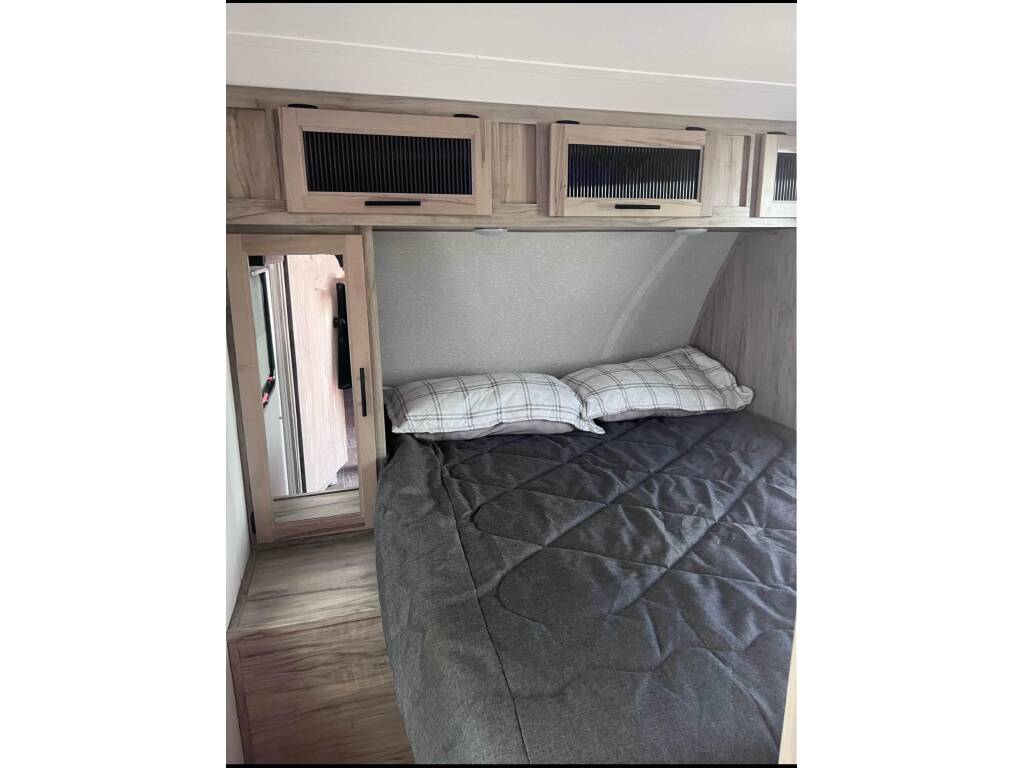 RV rental: A compact bedroom featuring a comfortable bed, wood-toned overhead cabinets, and a mirrored closet.. Forest River Cherokee Alpha Wolf 2022