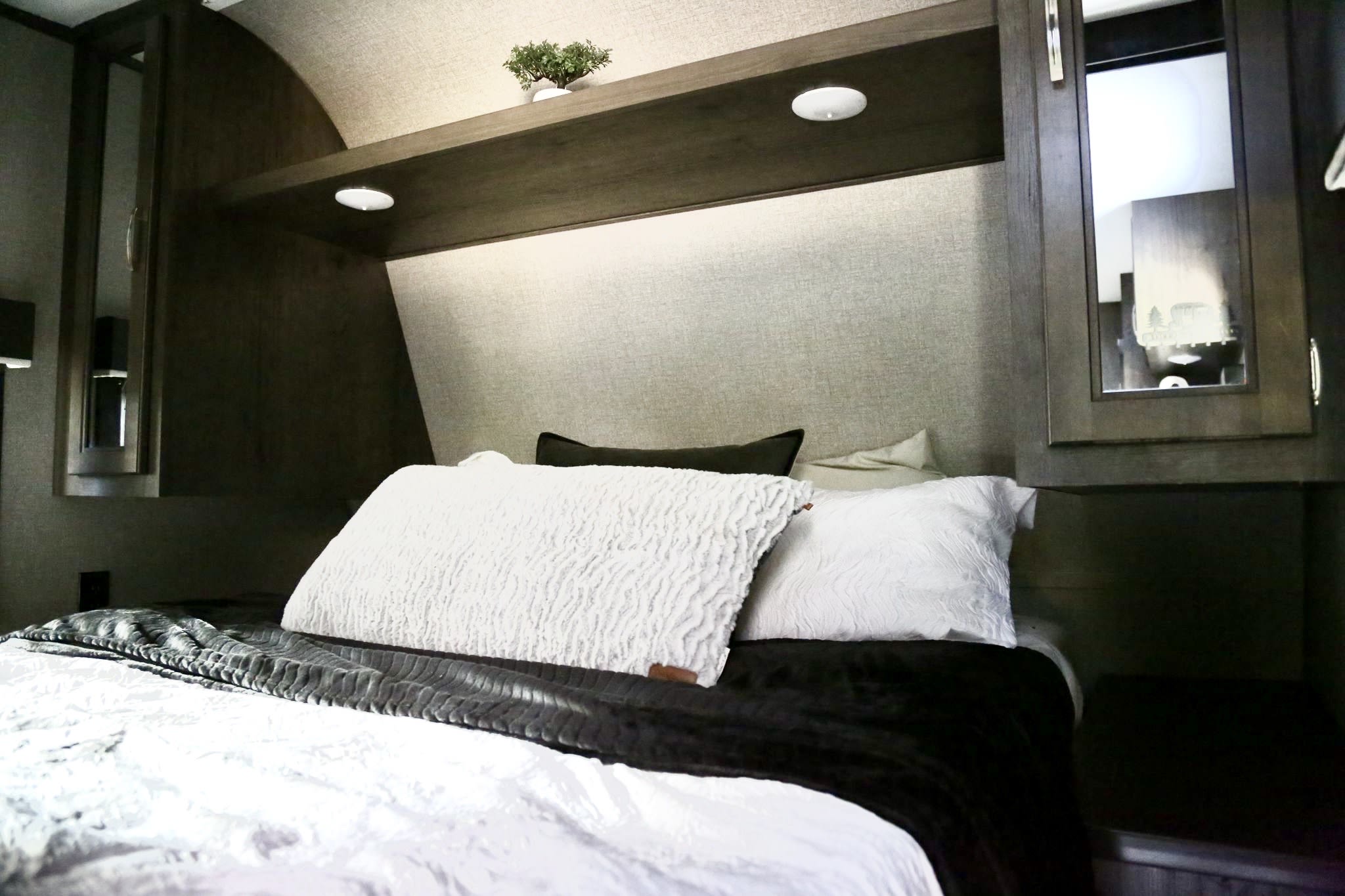 Modern RV rental bedroom features a plush bed, built-in shelving, and mirrored cabinets, offering comfort on the road.. Jayco Jay Flight SLX 2020