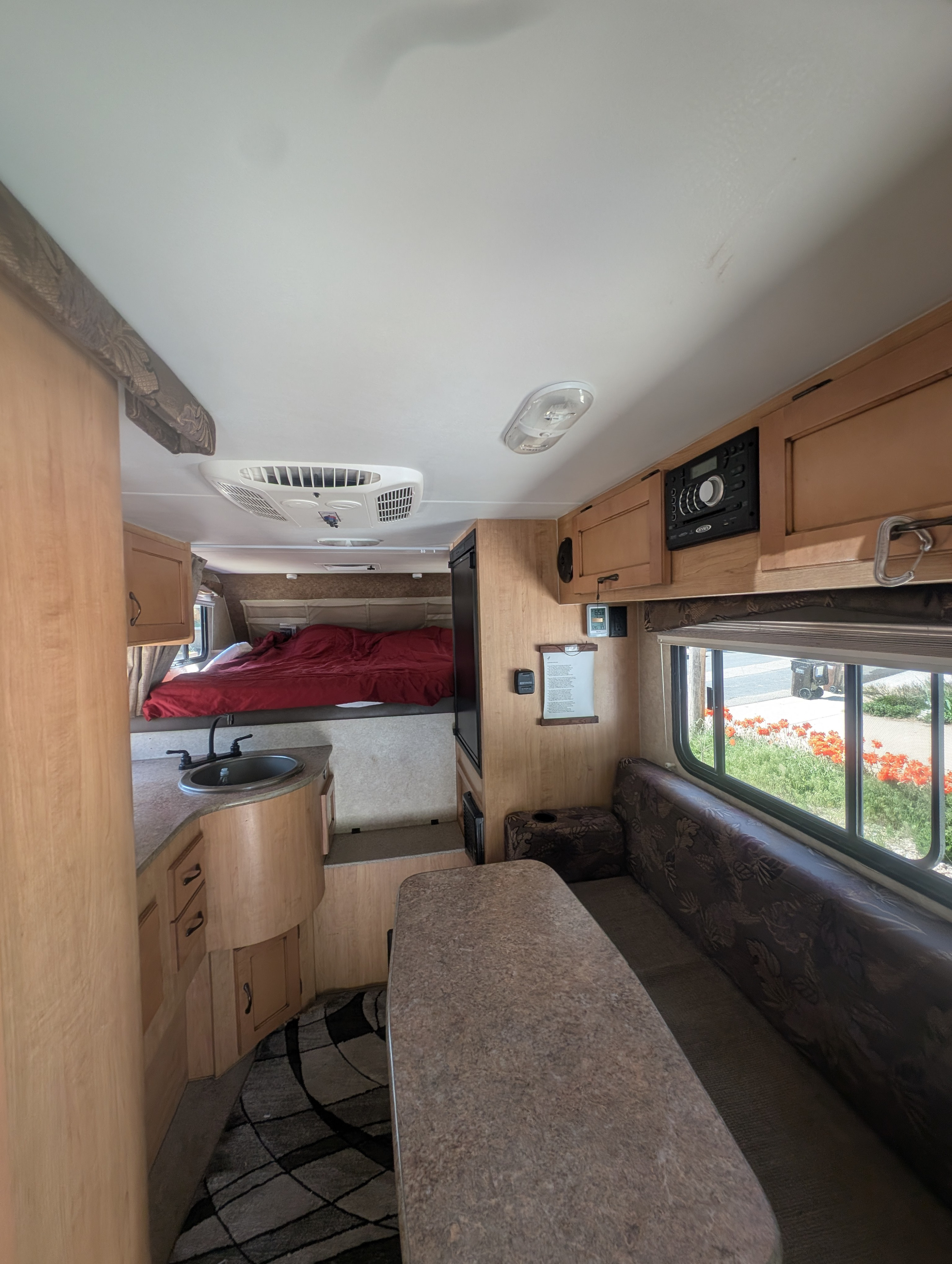 Explore this RV rental's interior: front bed, kitchen area with sink, and dinette table with bench seating.. Adventurer Adventurer 2015