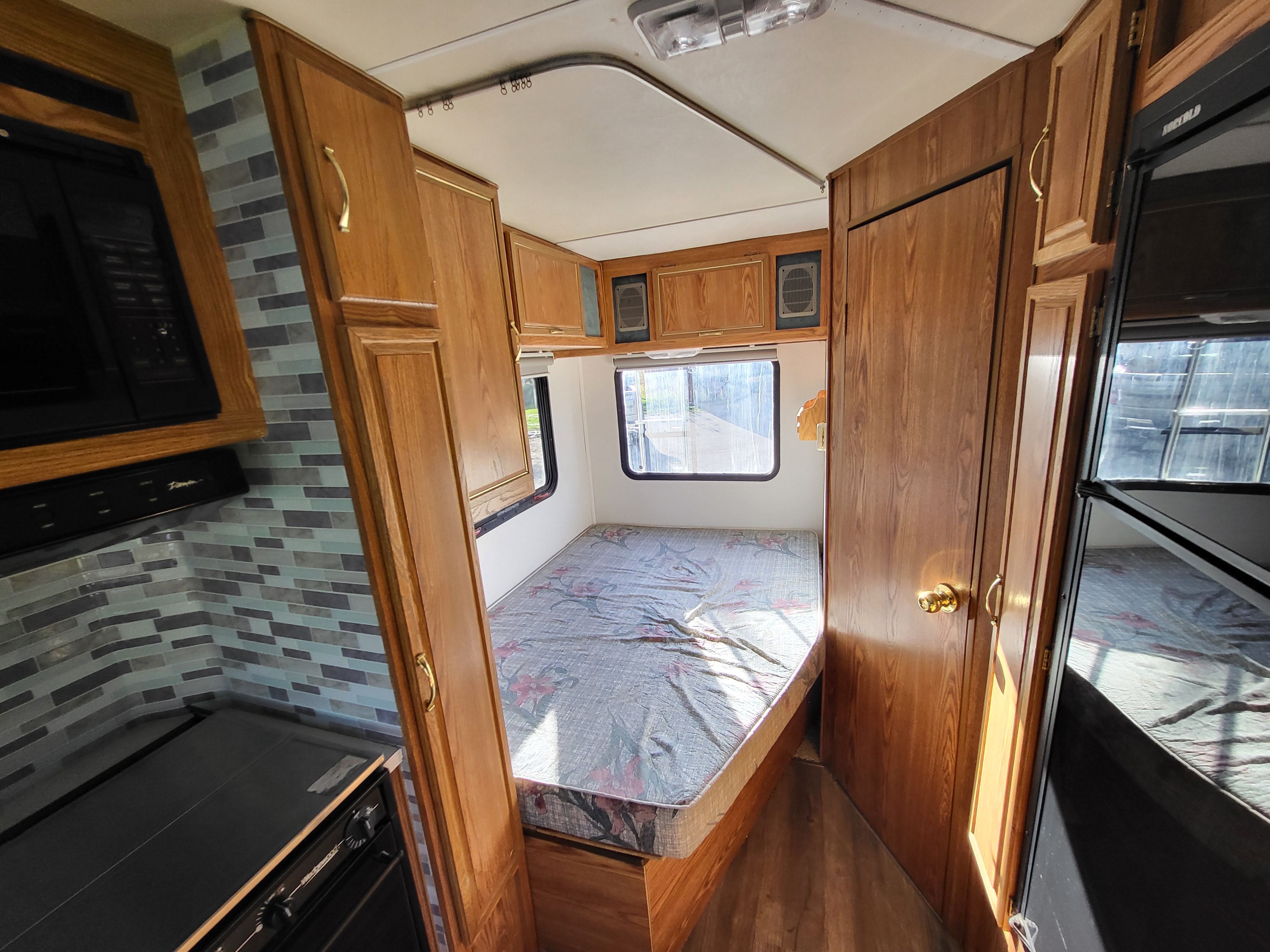 Inside this RV rental: a compact living space featuring a tiled kitchen, cozy bedroom, and built-in storage units.. Ford Econoline 1992