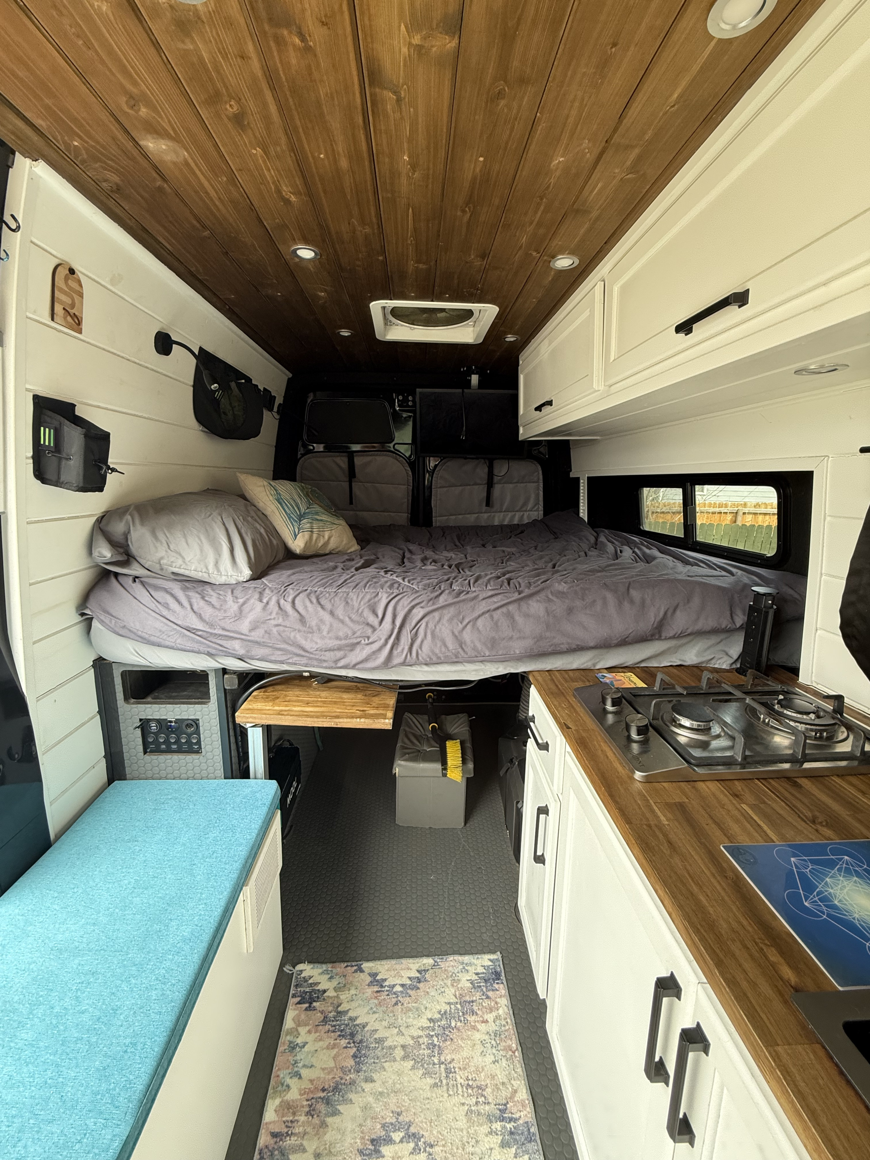 Cozy RV rental interior showcasing a comfortable bed, compact kitchen, and smart storage, ready for adventure.. Mercedes Sprinter 2023