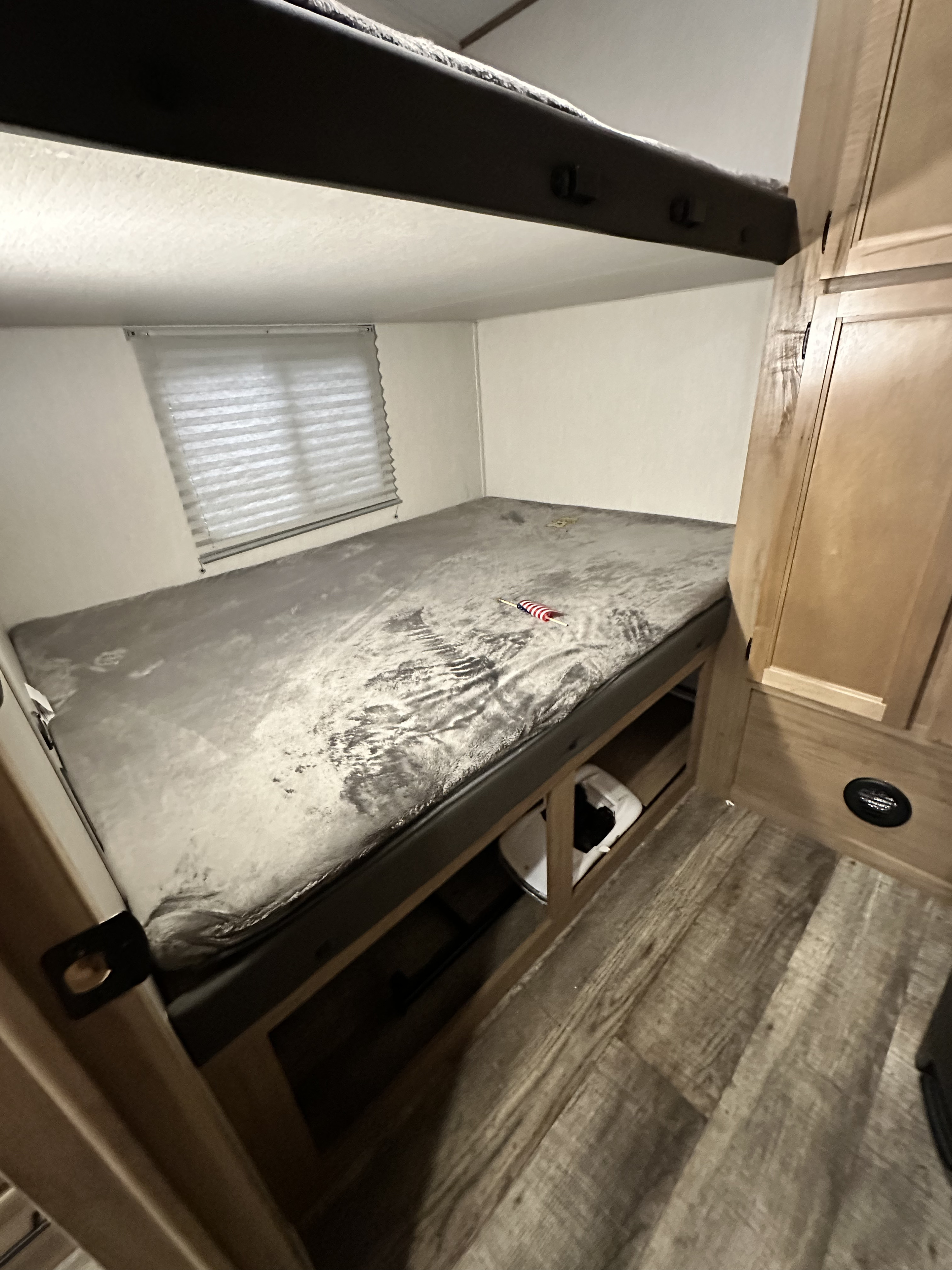 RV rental interior: compact bunk bed with storage, wood accents, and a window for comfortable travel accommodation.. Forest River Cherokee Arctic Wolf 2022