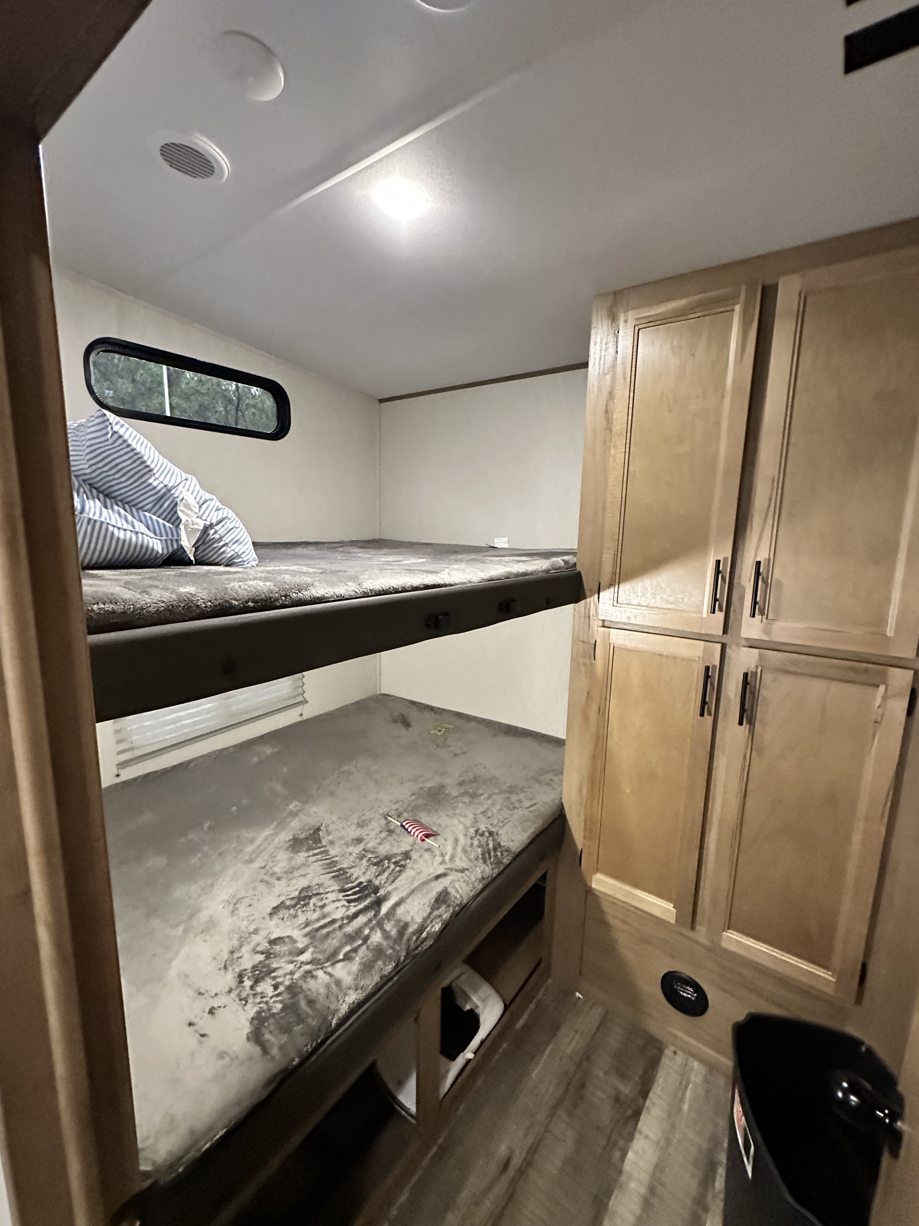 Inside an RV rental: view of bunk beds with bedding, wall cabinets, and under-bunk storage. Includes ceiling lights.. Forest River Cherokee Arctic Wolf 2022