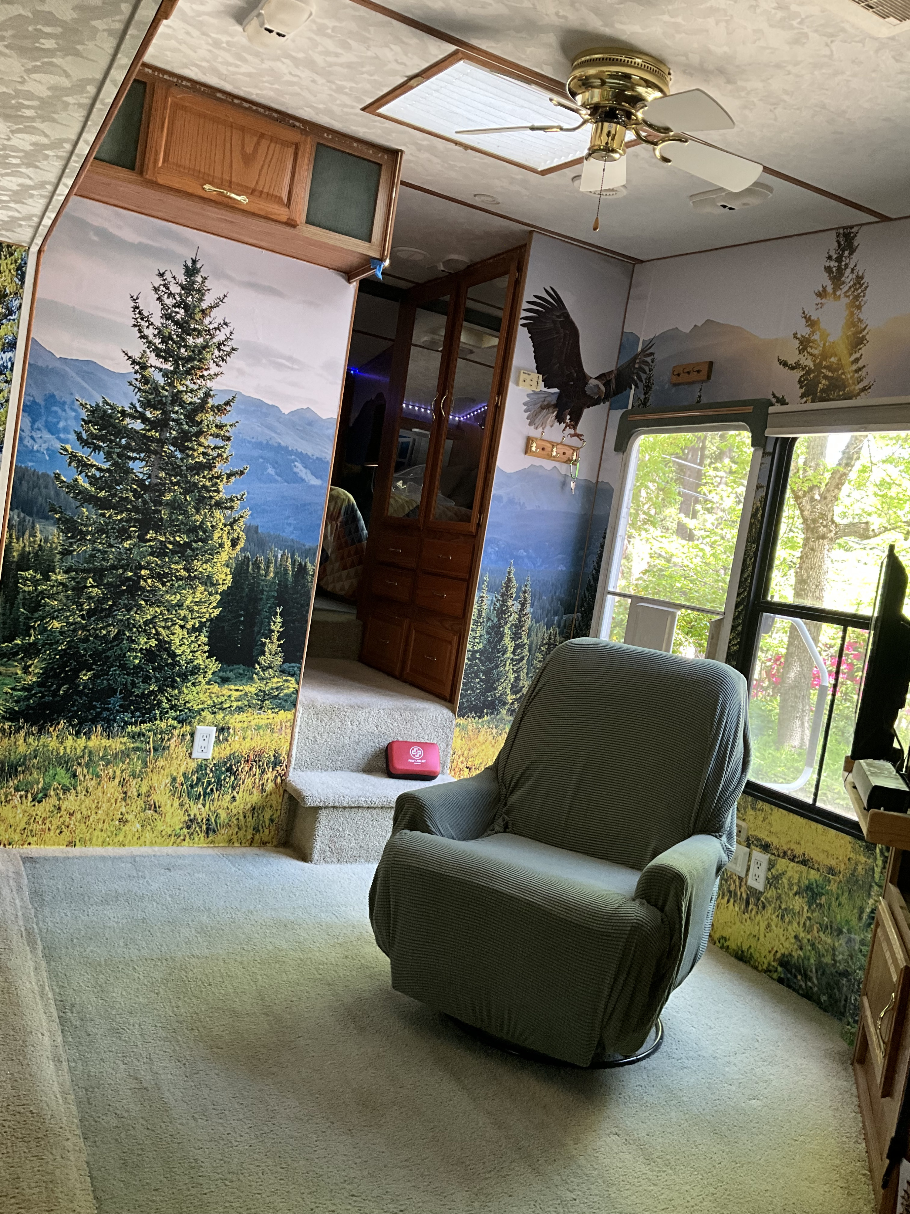 Cozy RV rental interior with scenic mountain mural walls, a comfy chair, and carpeted floors.. Komfort Komfort Fifth Wheel 2001
