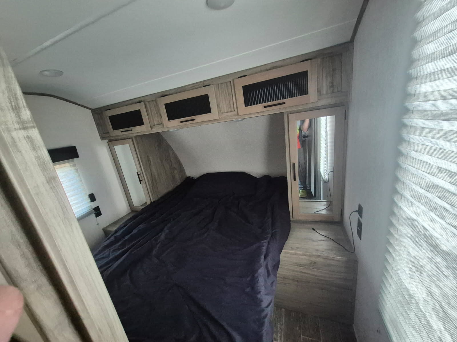 RV rental bedroom with a dark bed, overhead cabinets, and mirrored closets on either side. Includes window blinds.. Forest River Cherokee Alpha Wolf 2022