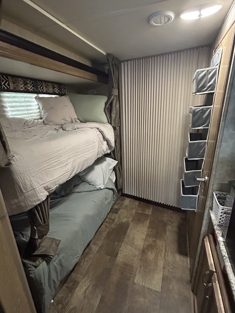 RV rental sleeping area featuring bunk beds, compact storage, and pleated shades.. Gulf Stream Conquest 2018