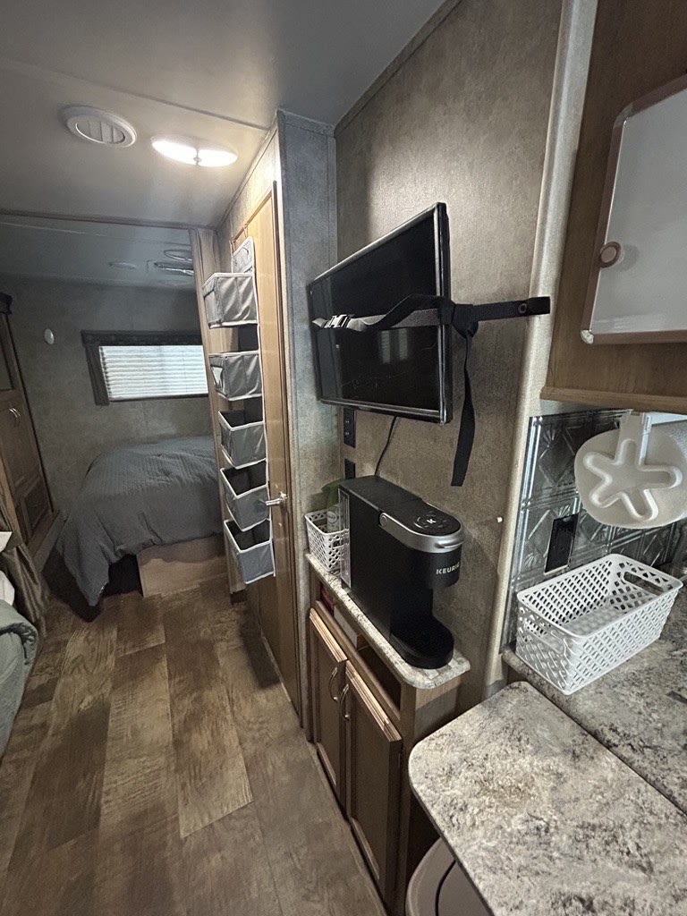 Cozy RV rental interior featuring a compact bedroom, mounted TV, Keurig coffee maker, and smart storage solutions.. Gulf Stream Conquest 2018