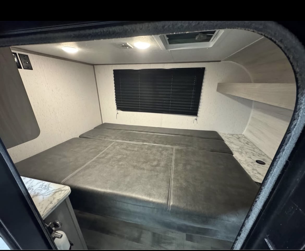 Inside your next RV rental: a versatile sleeping/seating area, window, ceiling vent, and handy storage shelves.. Coleman Rubicon 1200RK 2023