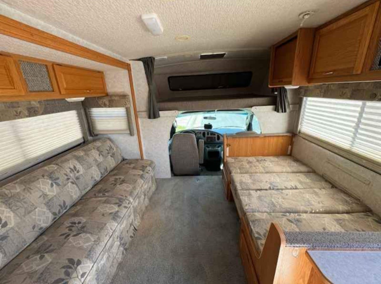 Inside an RV rental: a spacious living area featuring a sofa, convertible bed, and wood cabinets.. Itasca Spirit 2004