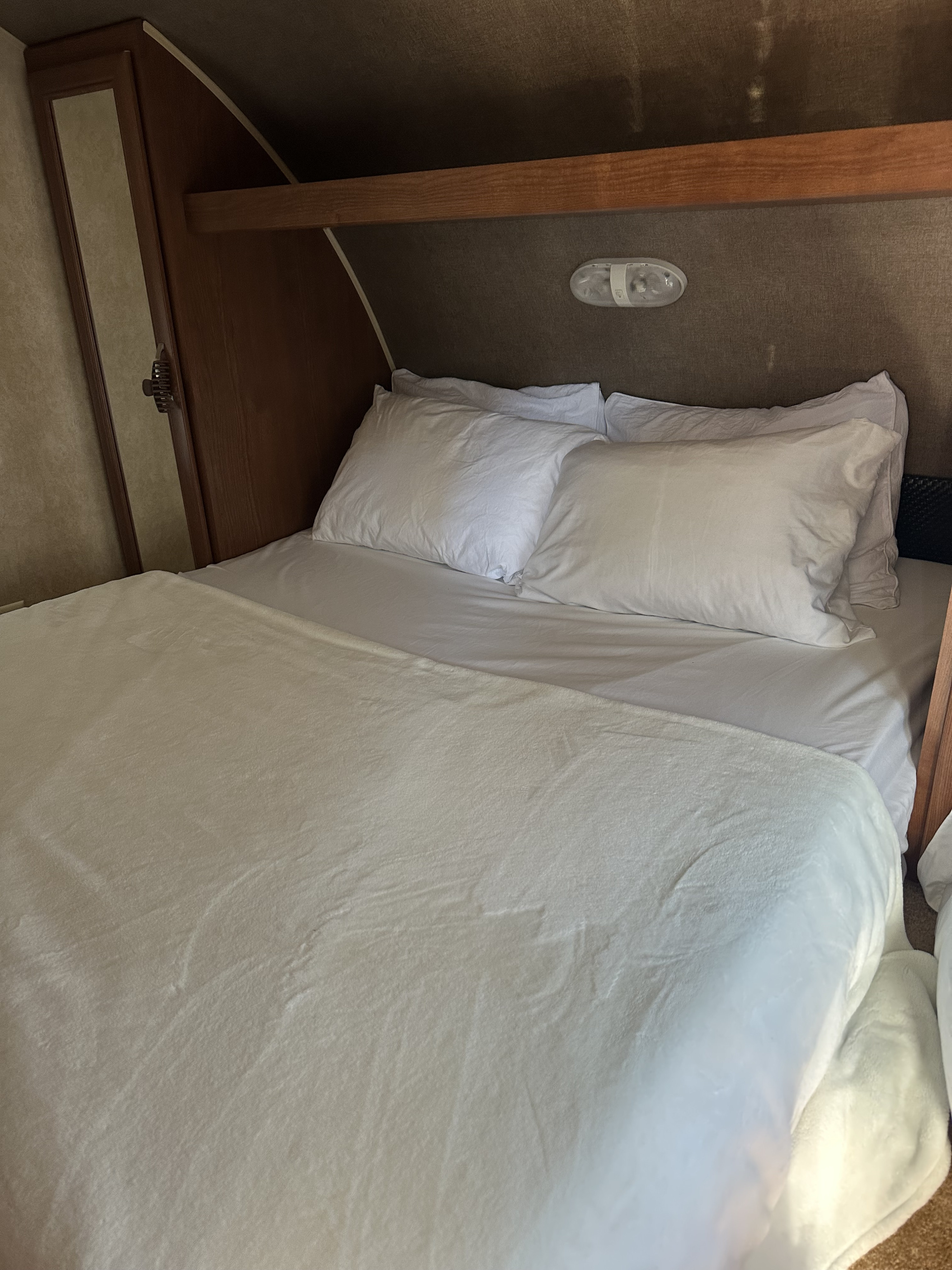 Clean, cozy RV rental bed with white linens, ready for a good night's sleep in a well-kept RV interior.. Forest River Salem 2016