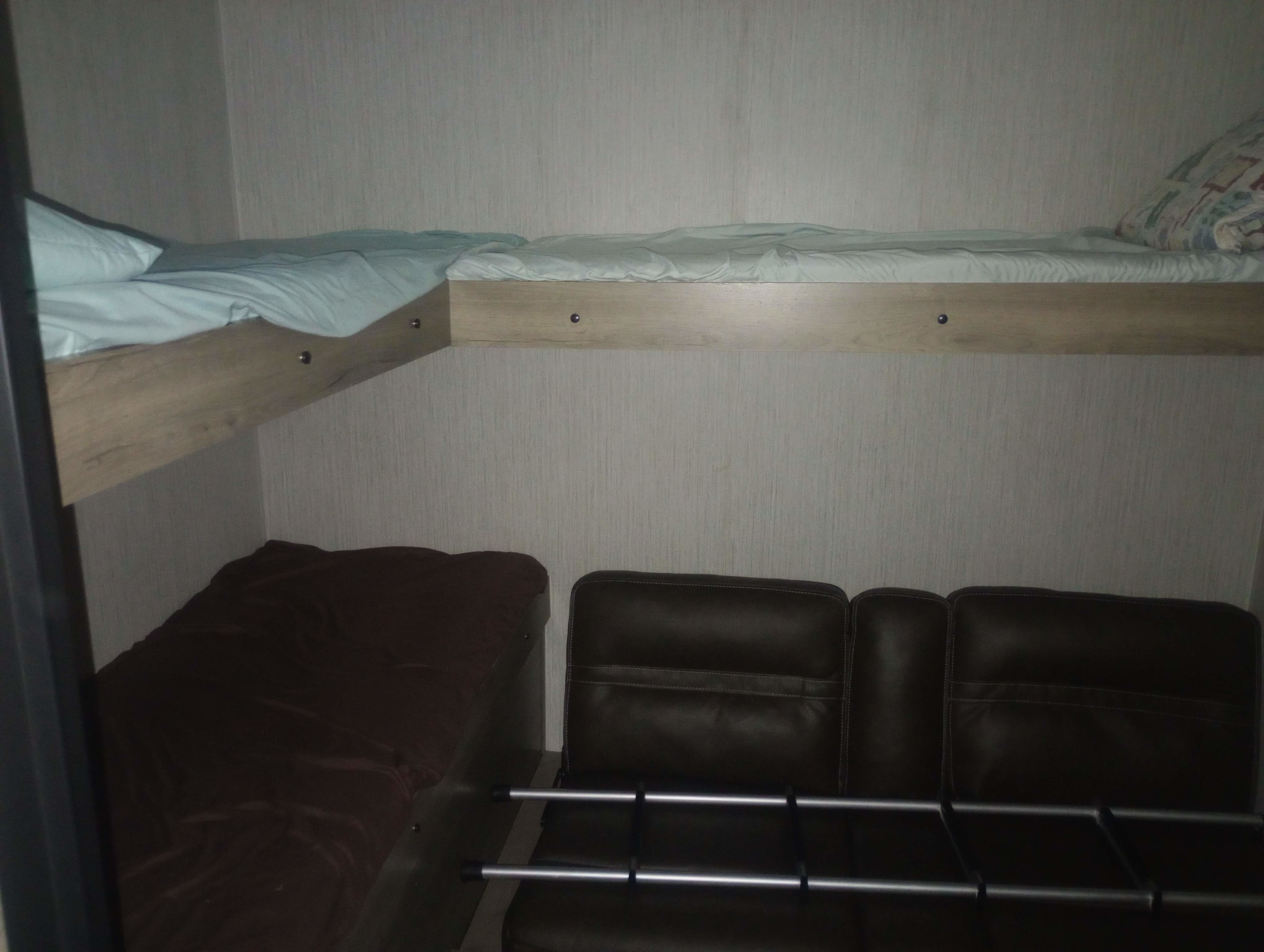 RV rental interior: cozy bunk beds with light blue sheets and a brown sofa, ideal for compact travel living.. Puma Palomino 28BHSS 2023