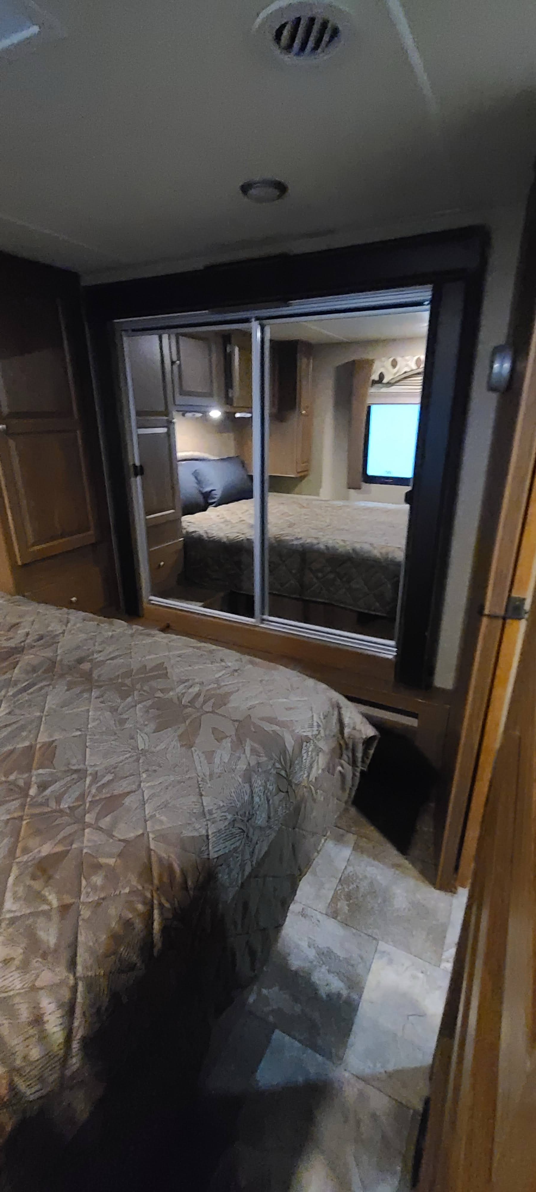 Step inside this cozy RV rental bedroom, featuring a comfortable bed, mirrored closet, and practical storage.. Forest River Coachmen Leprechaun 2015